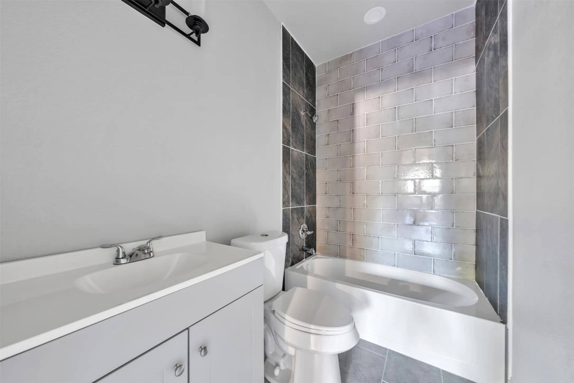 Modern bathroom featuring a built-in tub with light gray subway tile surround and dark gray accent tiling