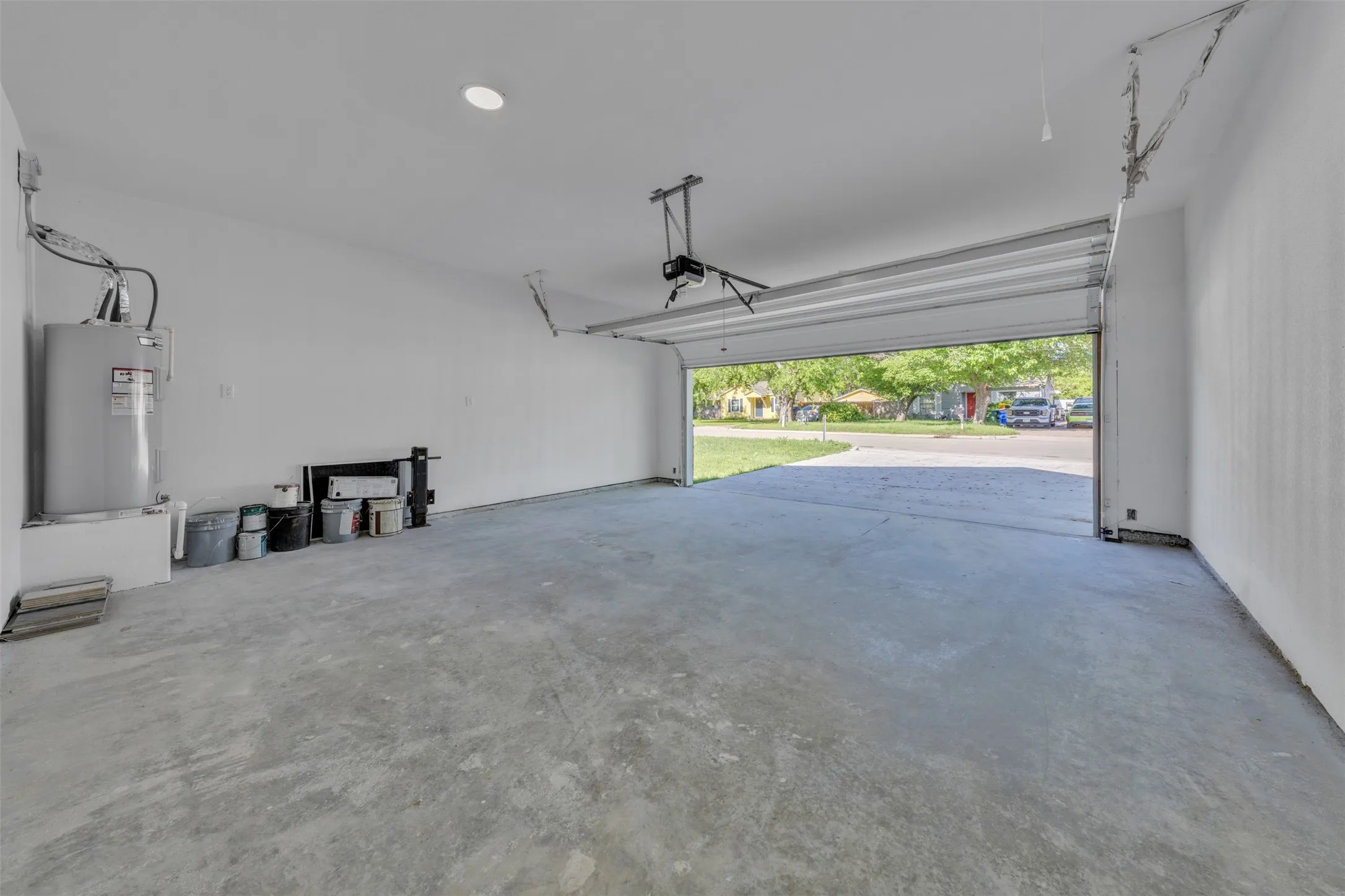 Spacious garage with an open overhead door, smooth concrete flooring, and a wall-mounted water heater