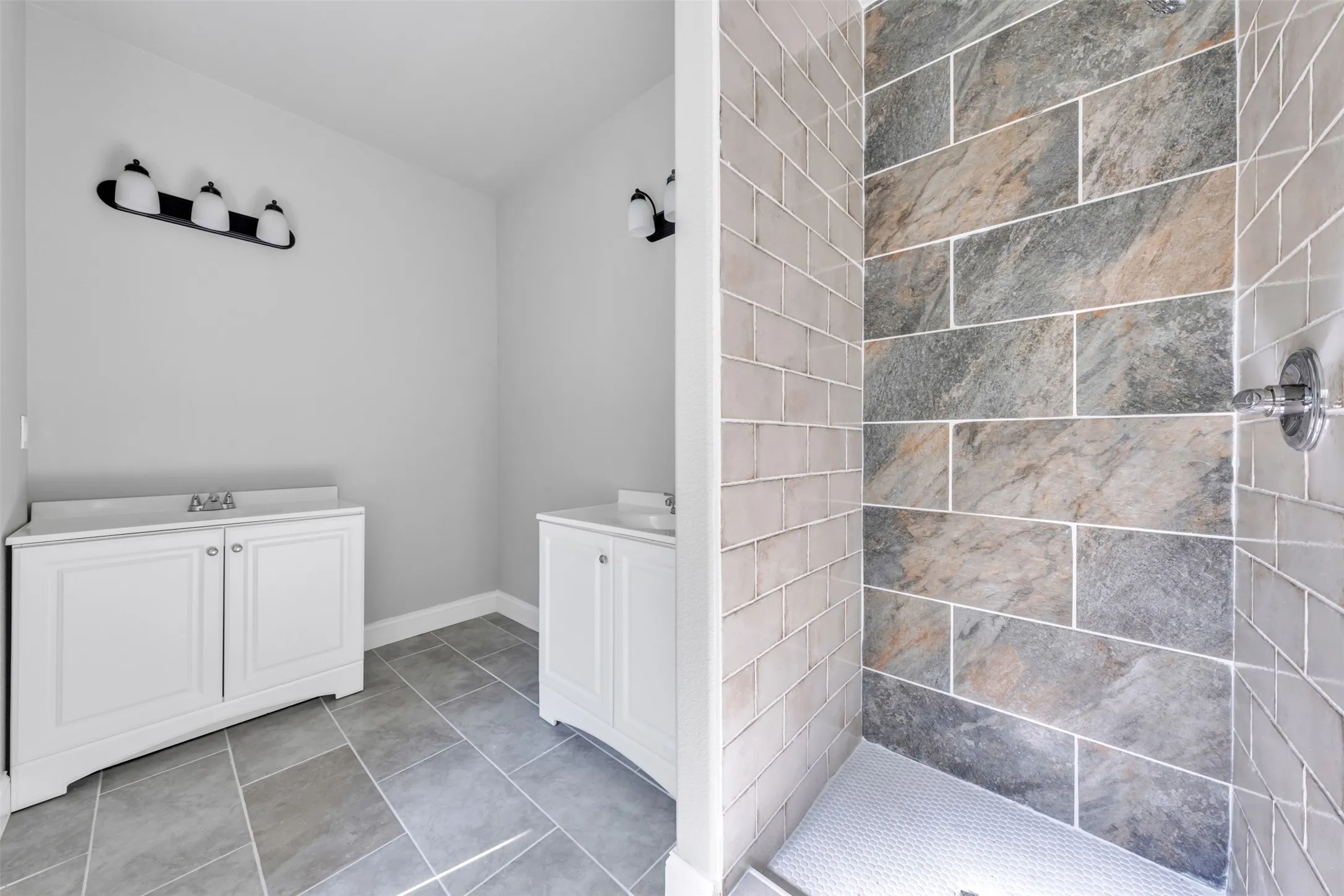 Spacious bathroom featuring a tiled shower with varied stone-look rectangular tiles and subway-style accent tiles