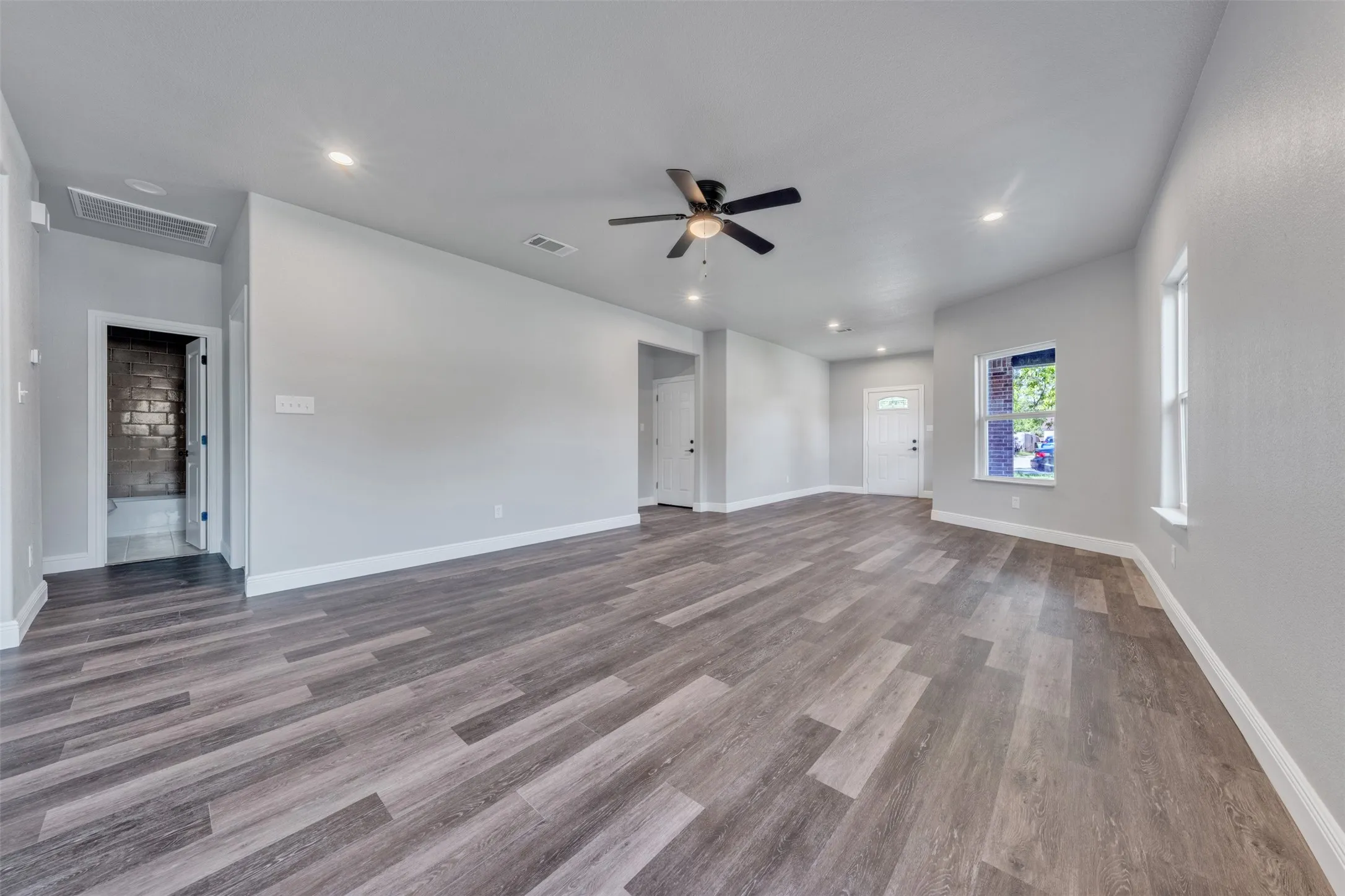 Spacious living area featuring wood-finish flooring, recessed lighting, a ceiling fan, and white baseboards