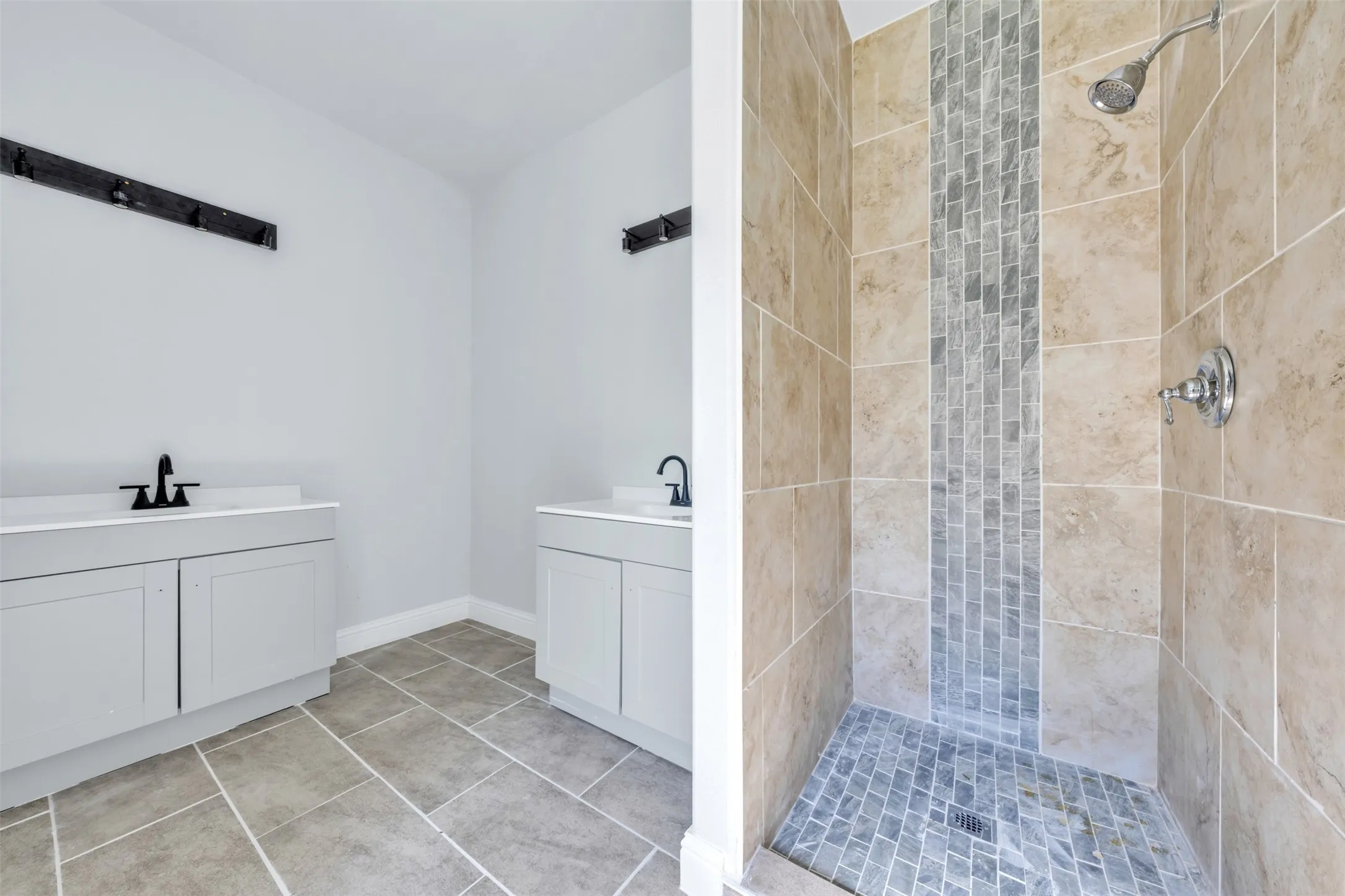 Tiled walk-in shower featuring a mosaic accent strip and a coordinating tiled floor