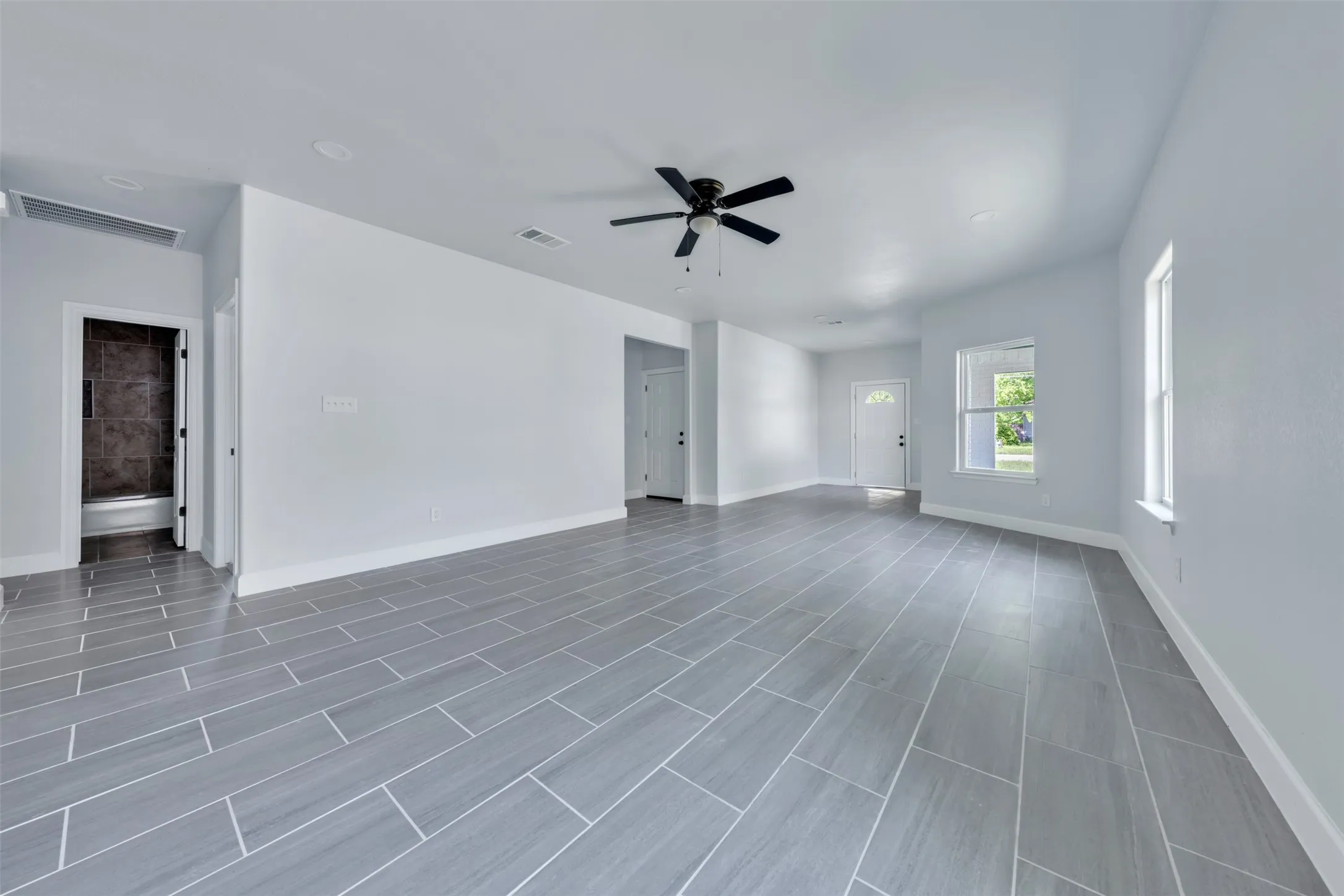 Open-concept living area featuring light gray plank tile flooring, recessed lighting, and a contemporary ceiling fan