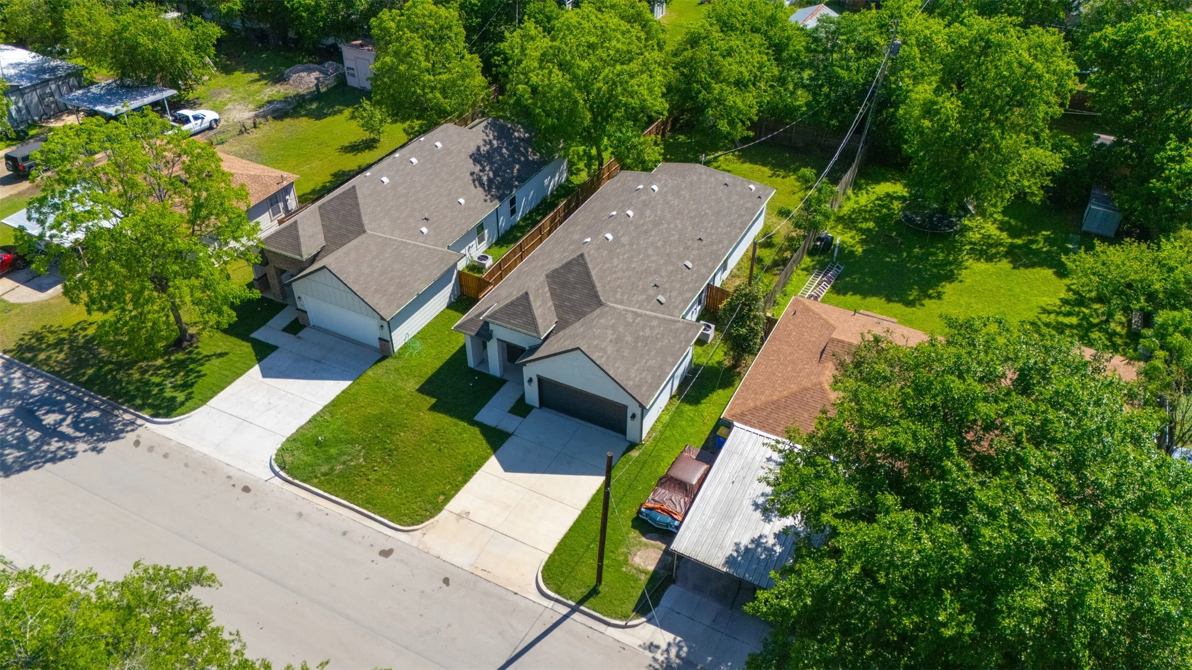 Modern residential property featuring a gray exterior, dark shingle roof, attached garage, concrete driveway, and manicured front lawn