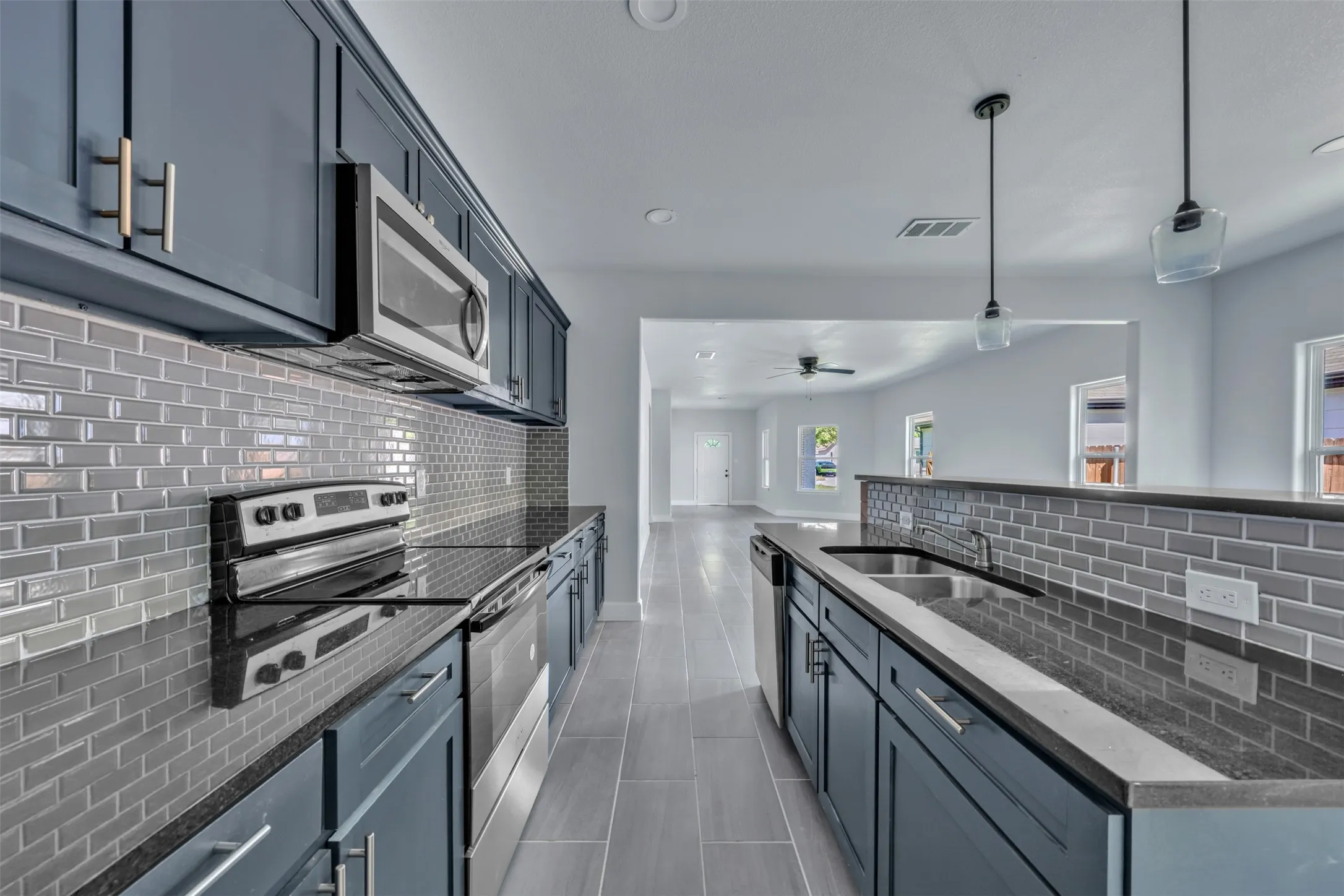 Kitchen featuring dark cabinetry, dark countertops, a subway tile backsplash, stainless steel appliances, and tile flooring