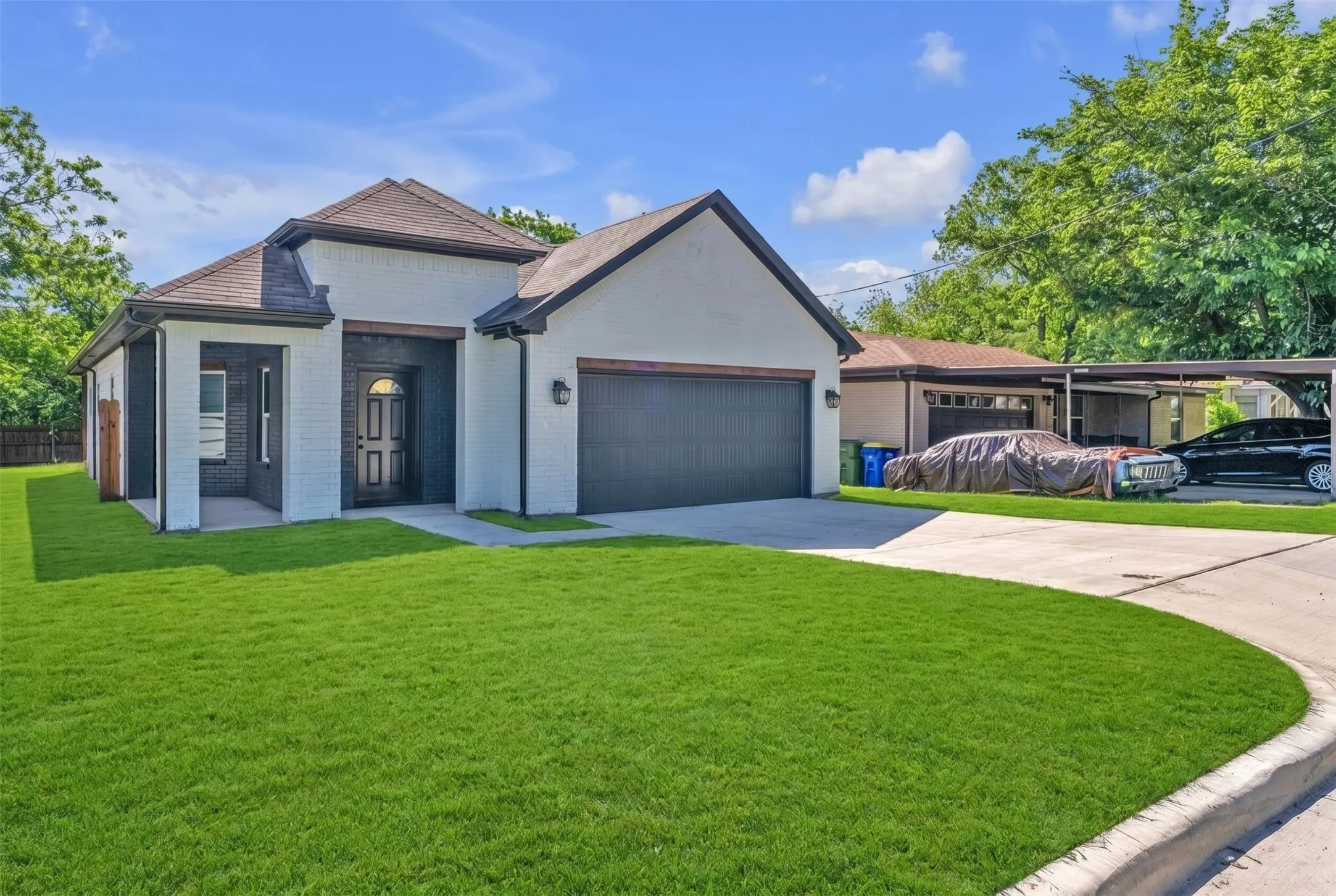 Contemporary exterior featuring a white brick facade with dark trim accents, a two-car garage with a dark door, and an inviting front entry with a dark door