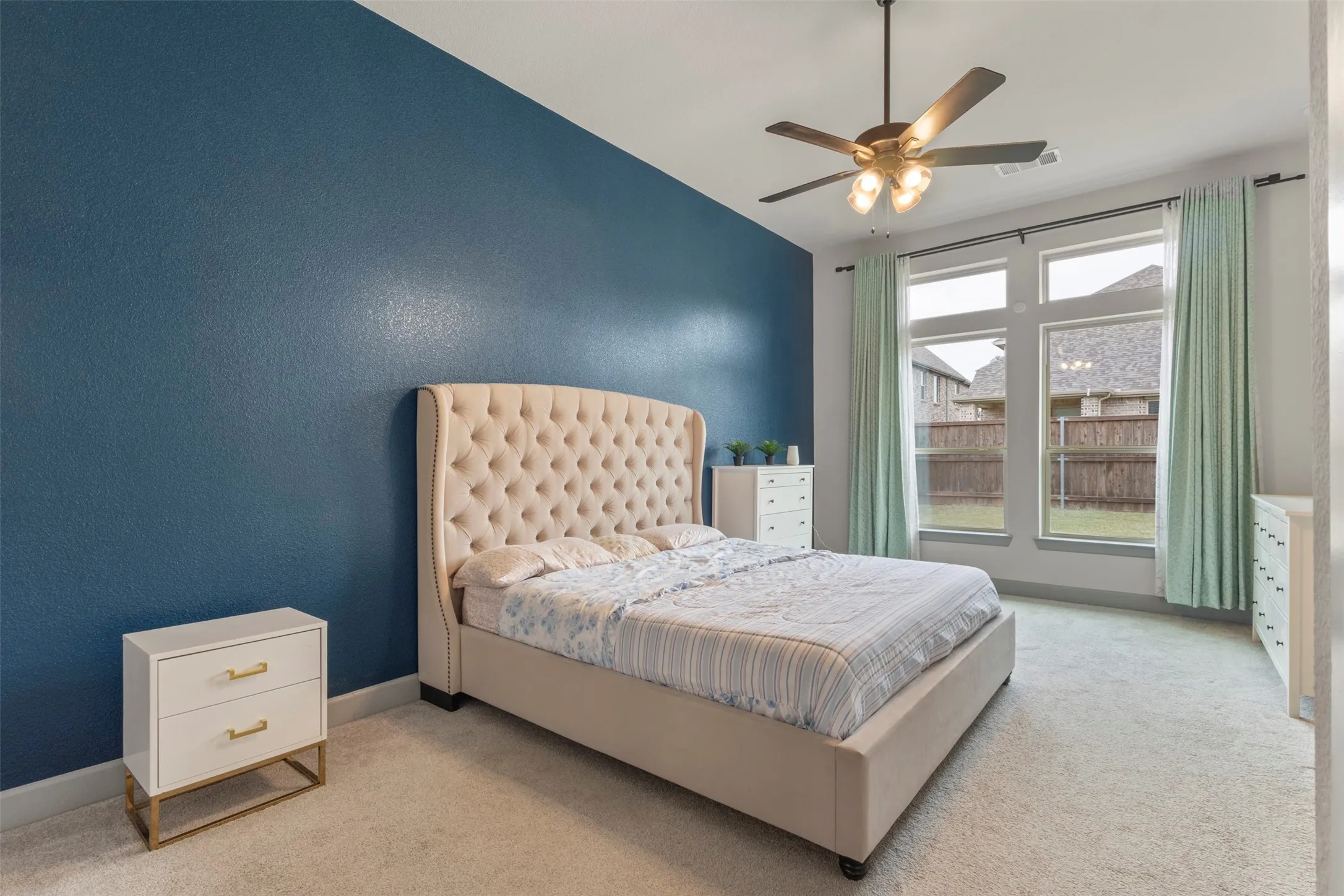Primary Bedroom featuring a dark blue accent wall, and light-colored carpeting