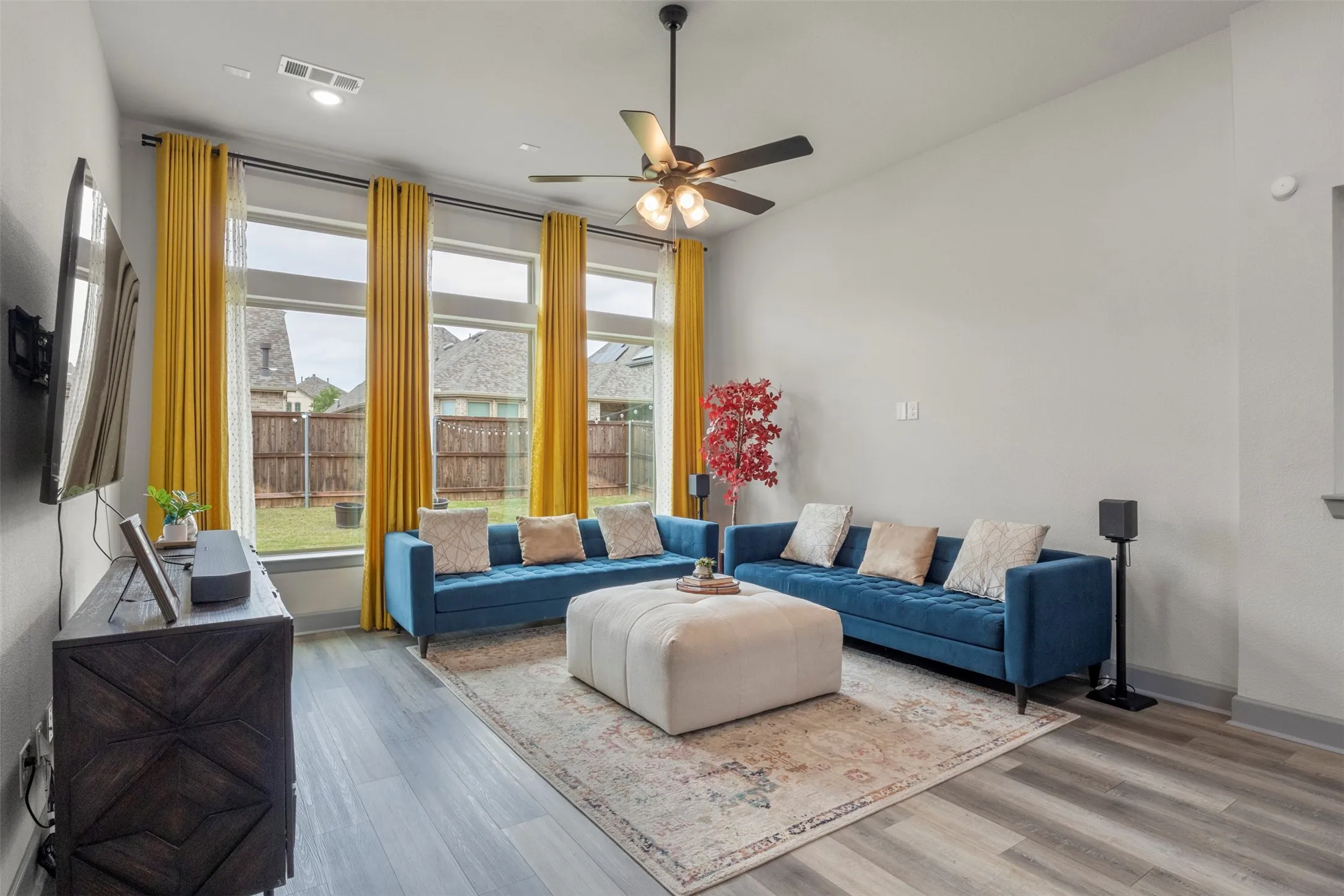 Bright living space featuring large windows, durable LVP flooring, recessed lighting, and a ceiling fan