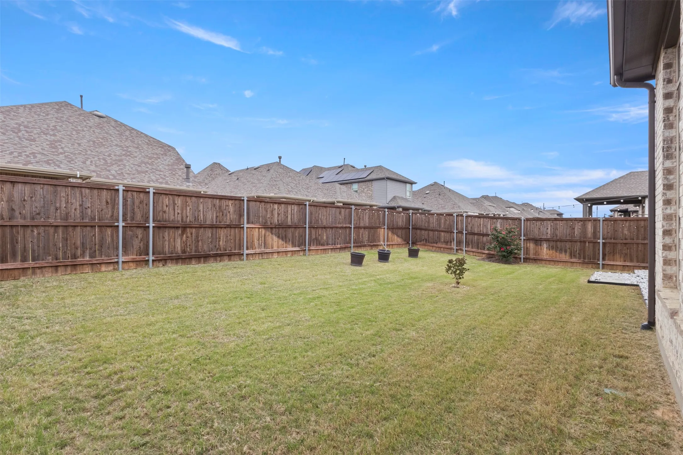 Expansive backyard featuring a manicured lawn, full wood privacy fencing