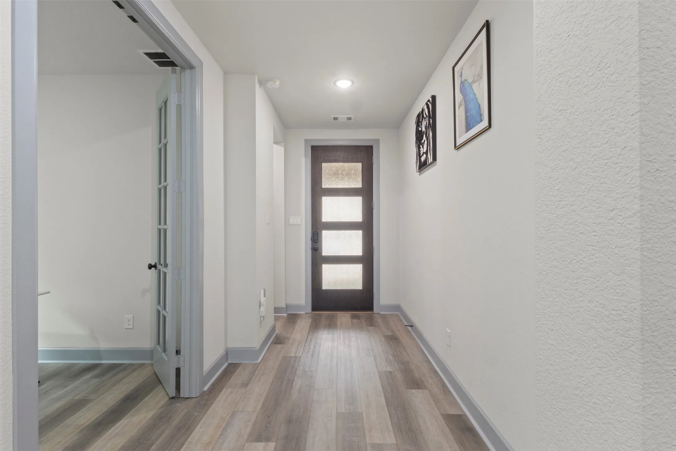Entryway featuring LVP flooring, a contemporary front door with frosted glass panels, recessed ceiling lighting.