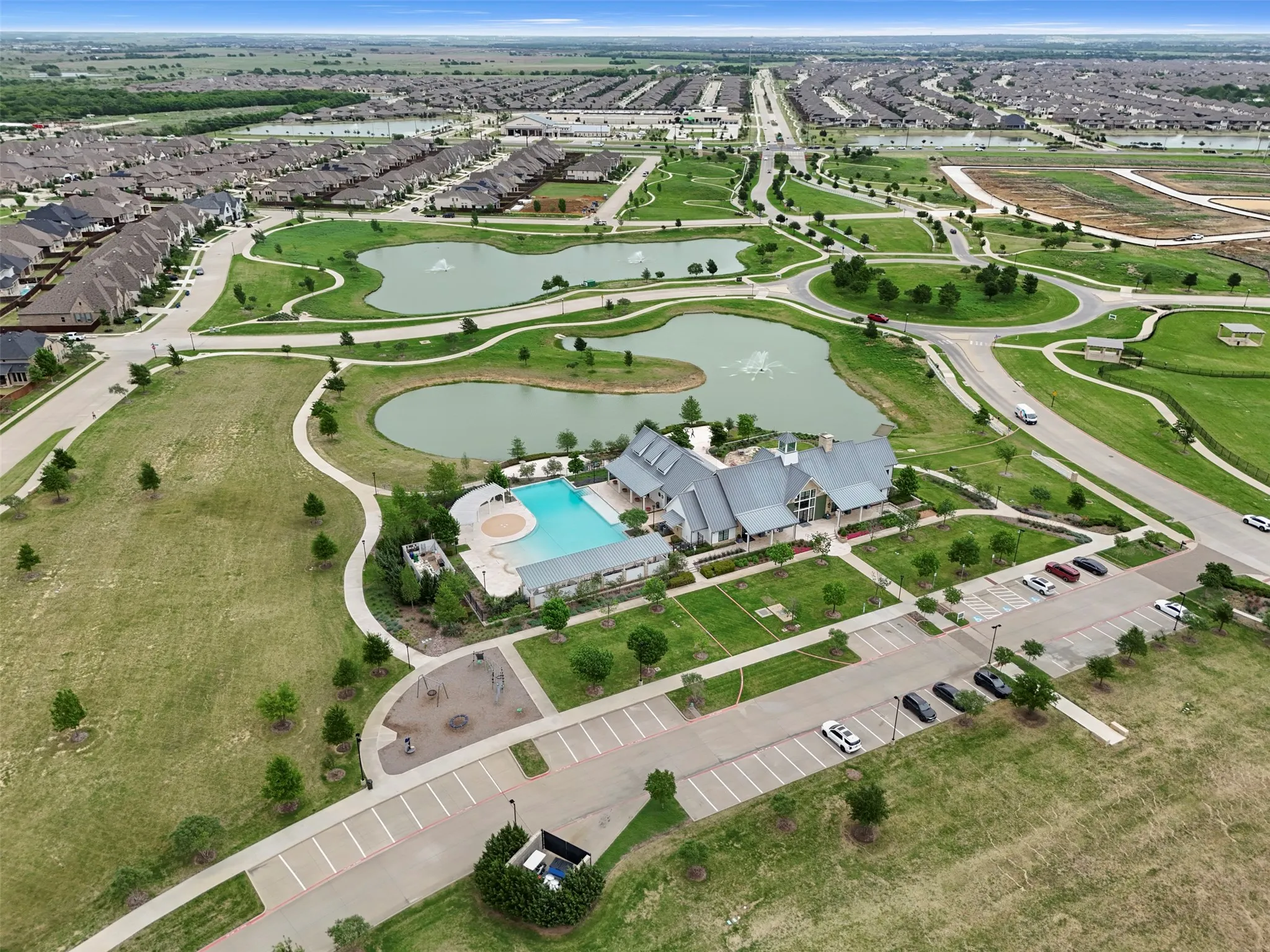 View of the Carriage House Amenity Center. Includes the workout facility, the back porch with seating and large firepit and an infinity edge pool with kids splash area.