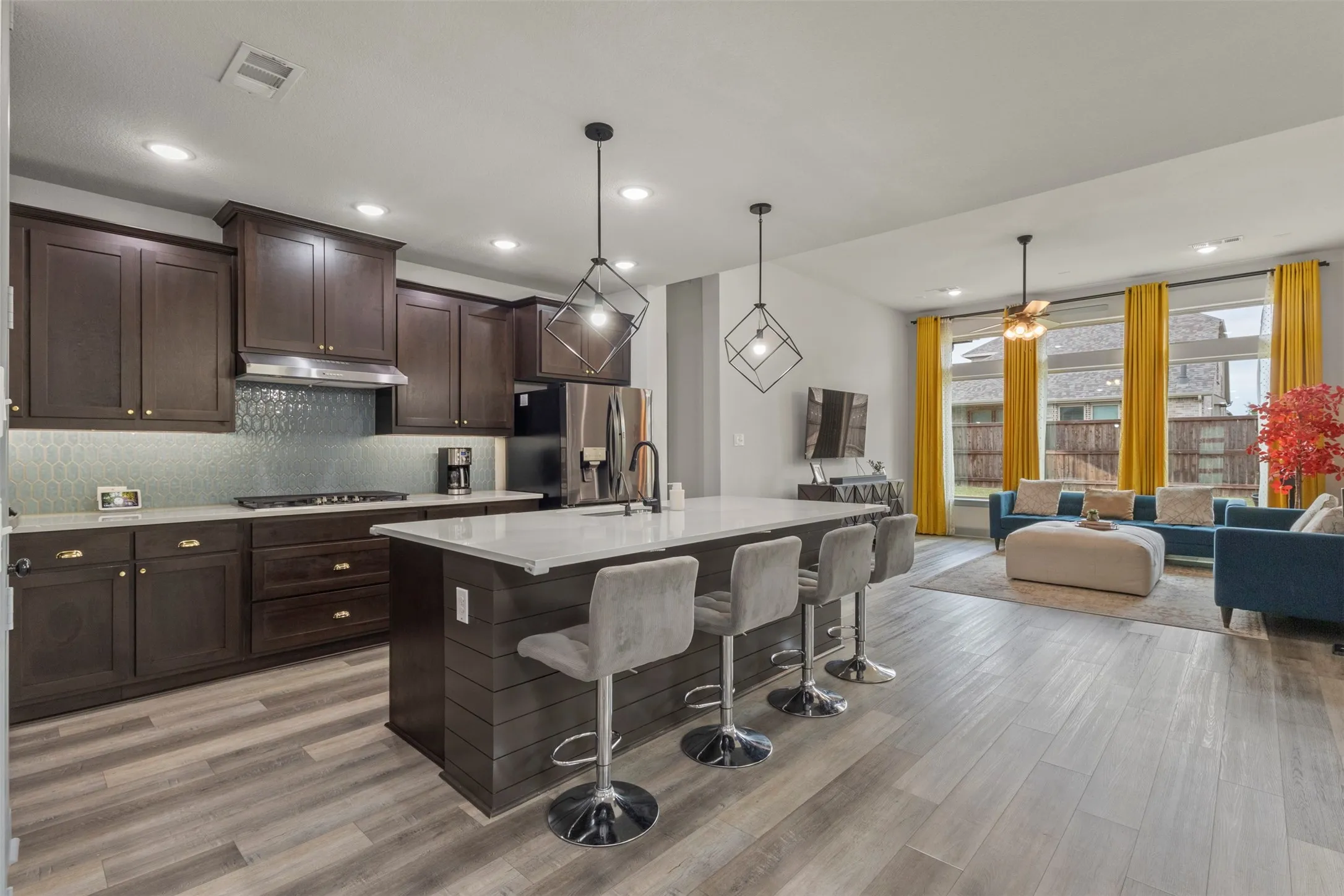 Open-concept living space featuring a kitchen island with seating, dark wood cabinetry, stainless steel appliances, and LVP flooring