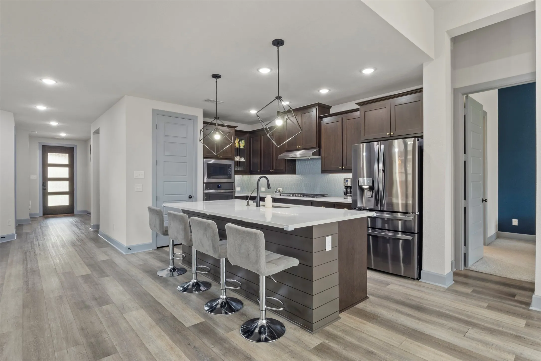 Modern kitchen featuring dark wood cabinetry, stainless steel appliances, and a central island with a quartz countertop