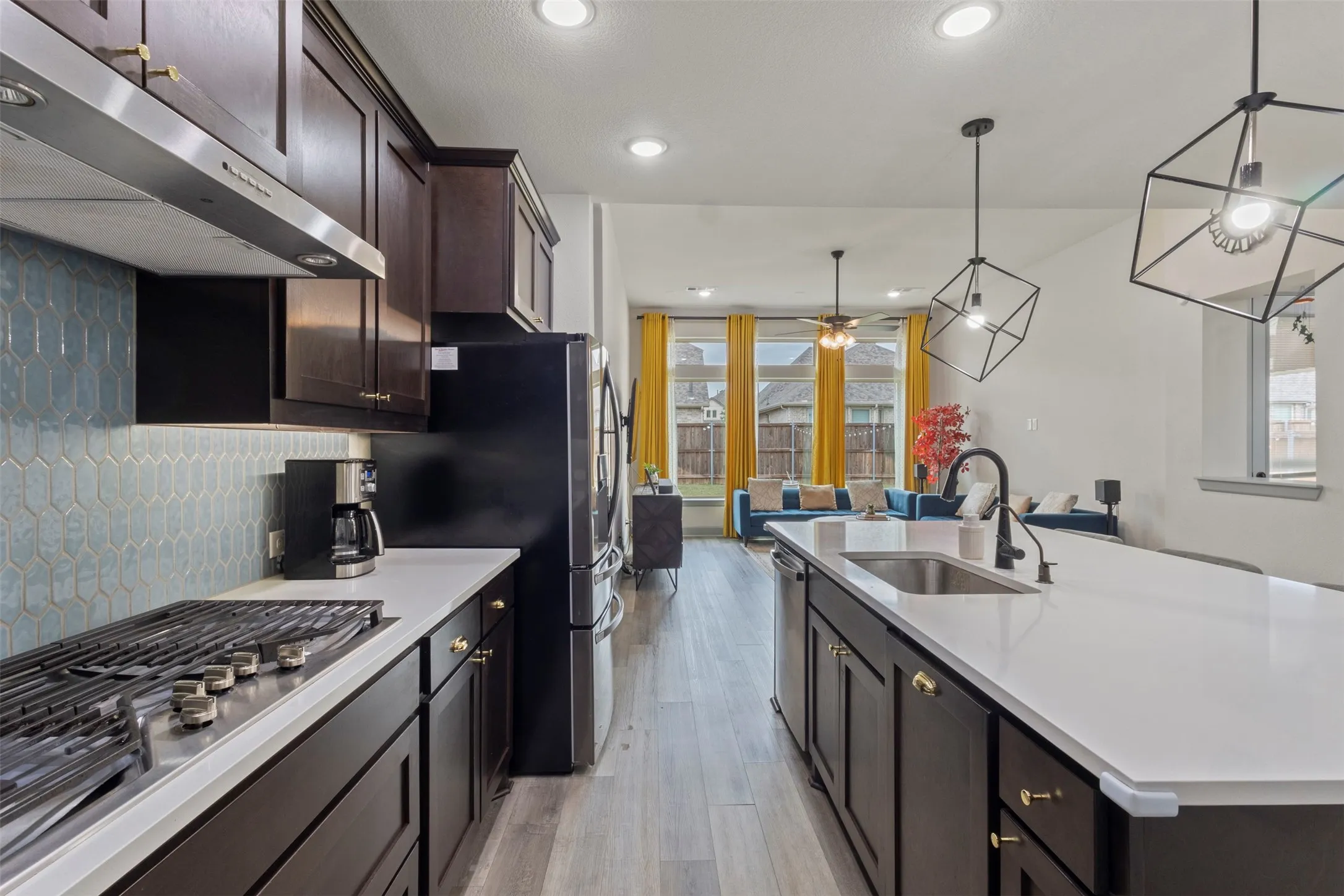 Gourmet kitchen with dark wood cabinetry, quartz countertops, built-in gas range, and a geometric tile backsplash