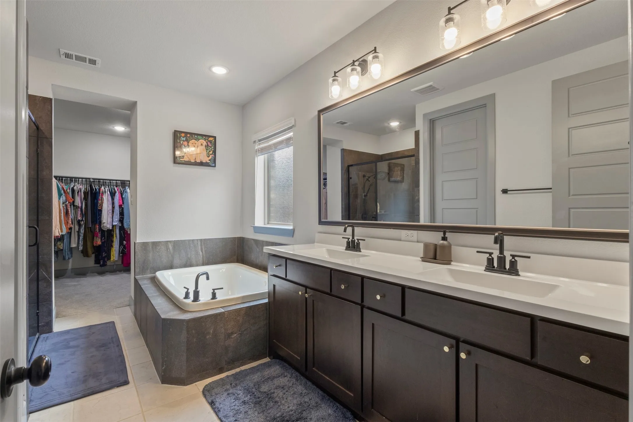 Bathroom featuring a dual vanity with dark wood cabinetry and white countertops
