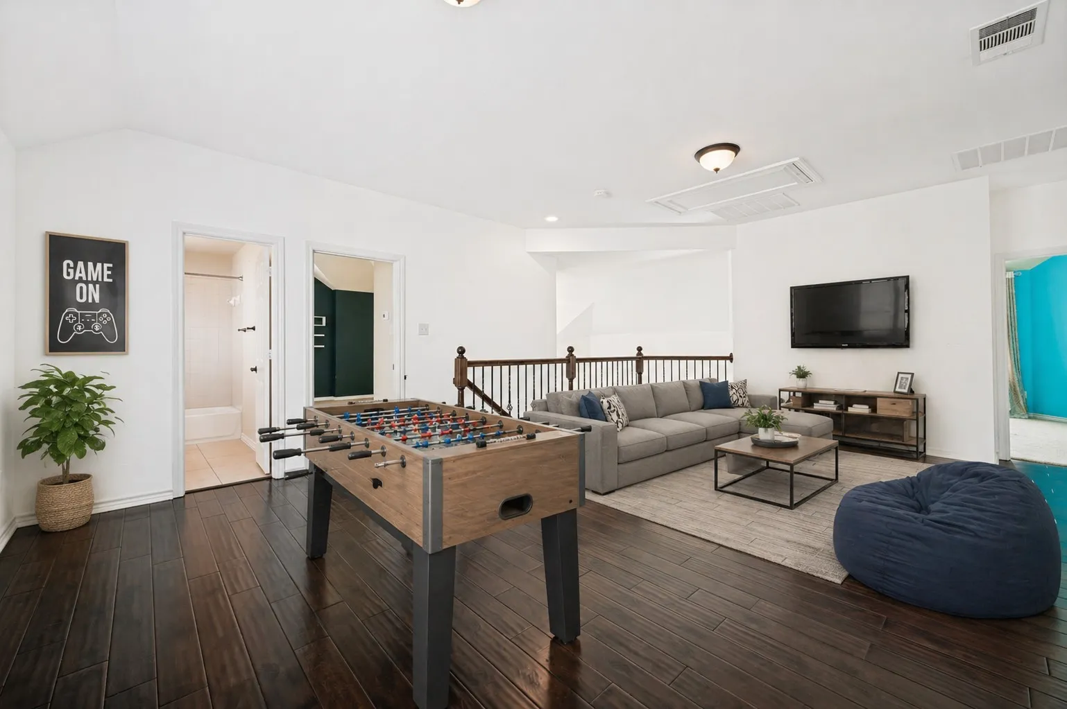 Spacious upstairs loft featuring dark wood-finish flooring, white walls, and a recessed ceiling. virtually staged photo