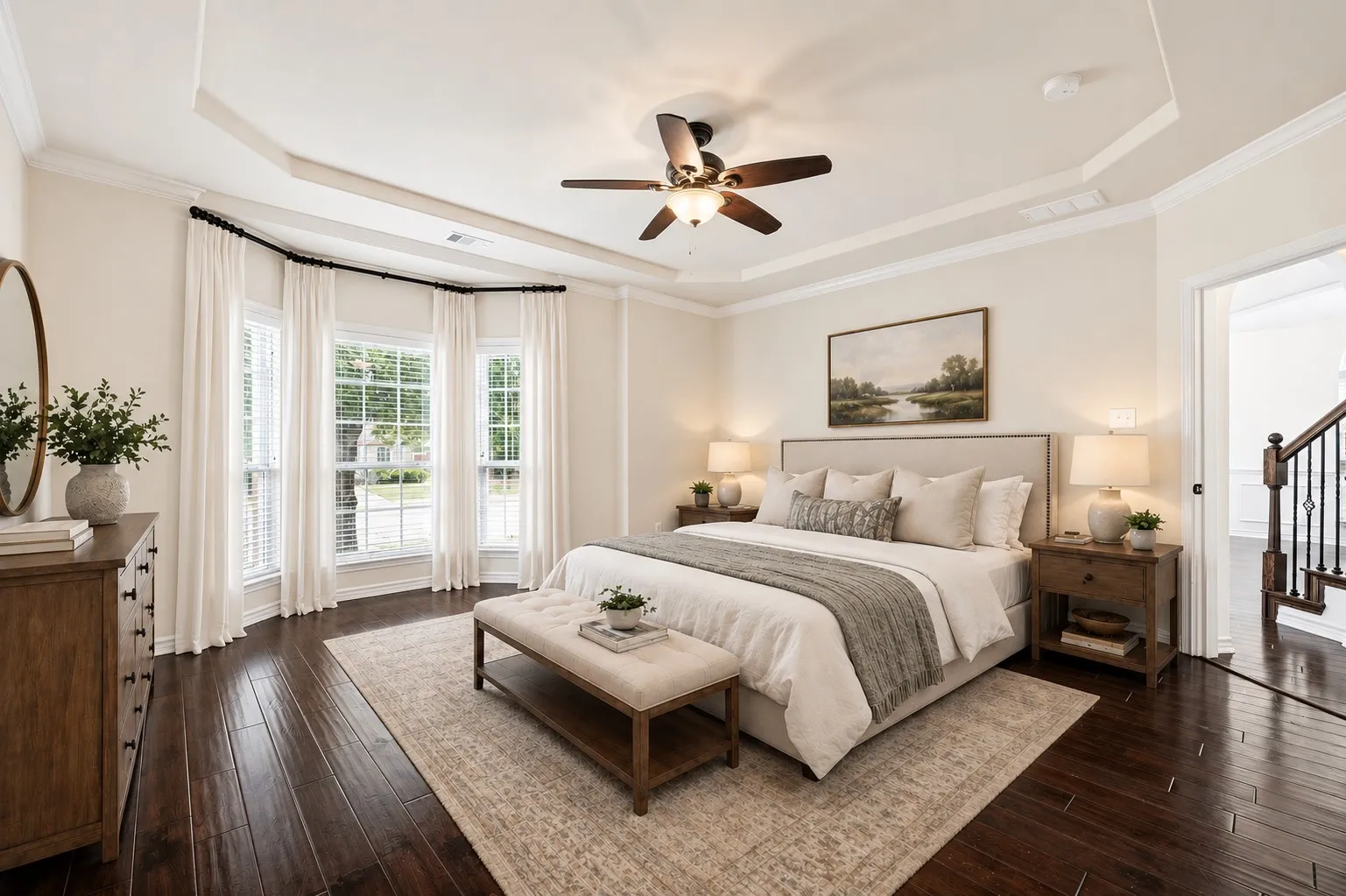 Tray ceiling with crown molding, ceiling fan, dark wood-finish flooring, bay window, virtually staged