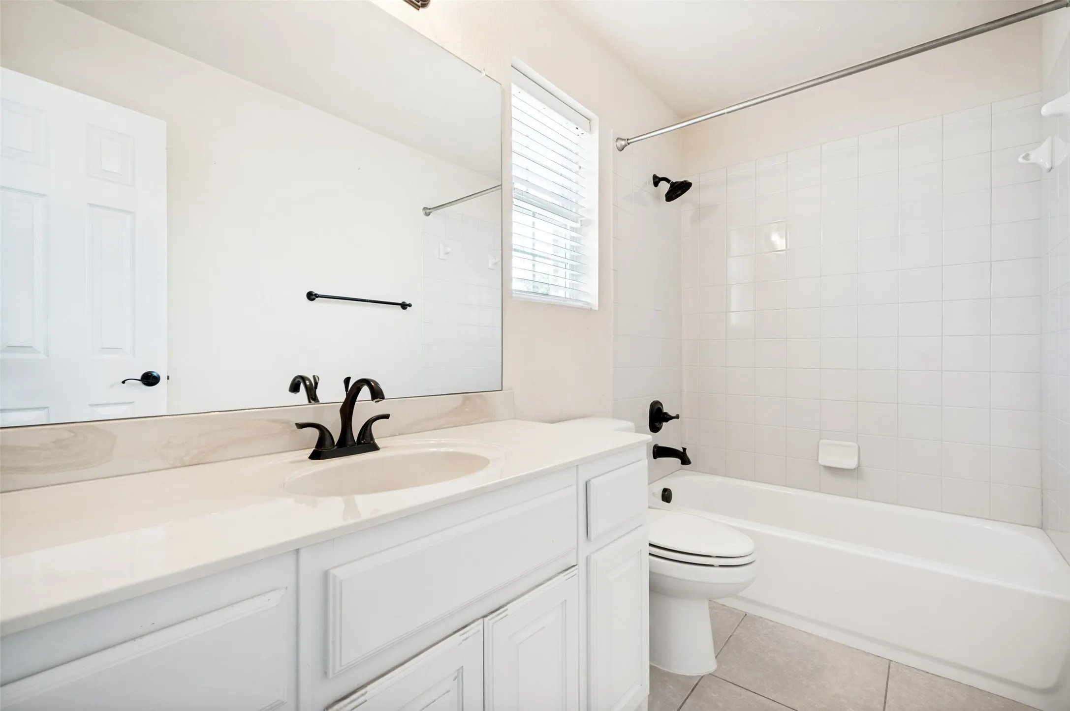 Bathroom featuring a white vanity with an integrated sink, matte black faucet, and a large wall-mounted mirror