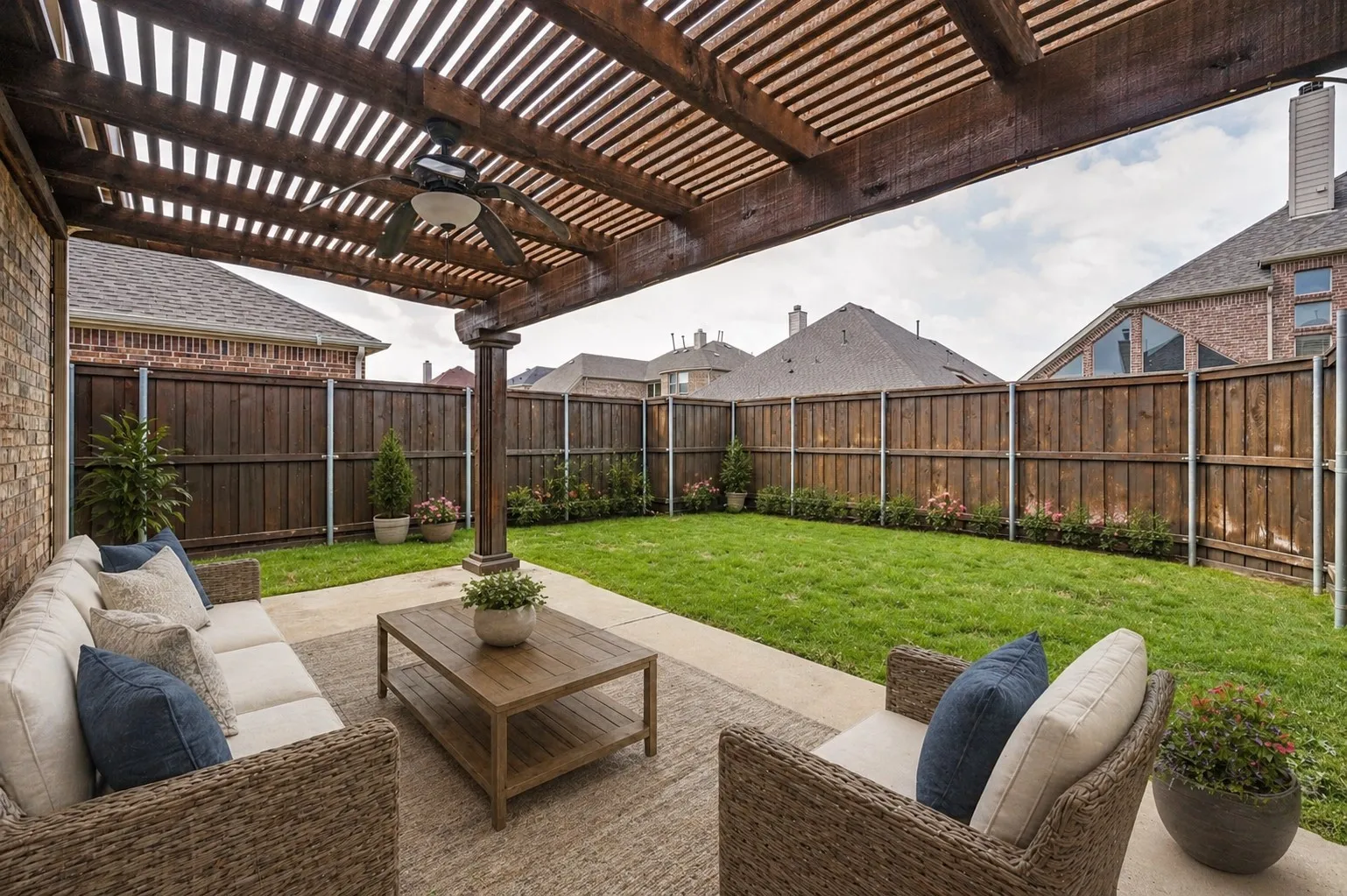 Covered patio featuring a wood pergola and ceiling fan, concrete flooring, and brick exterior. virtually staged photo