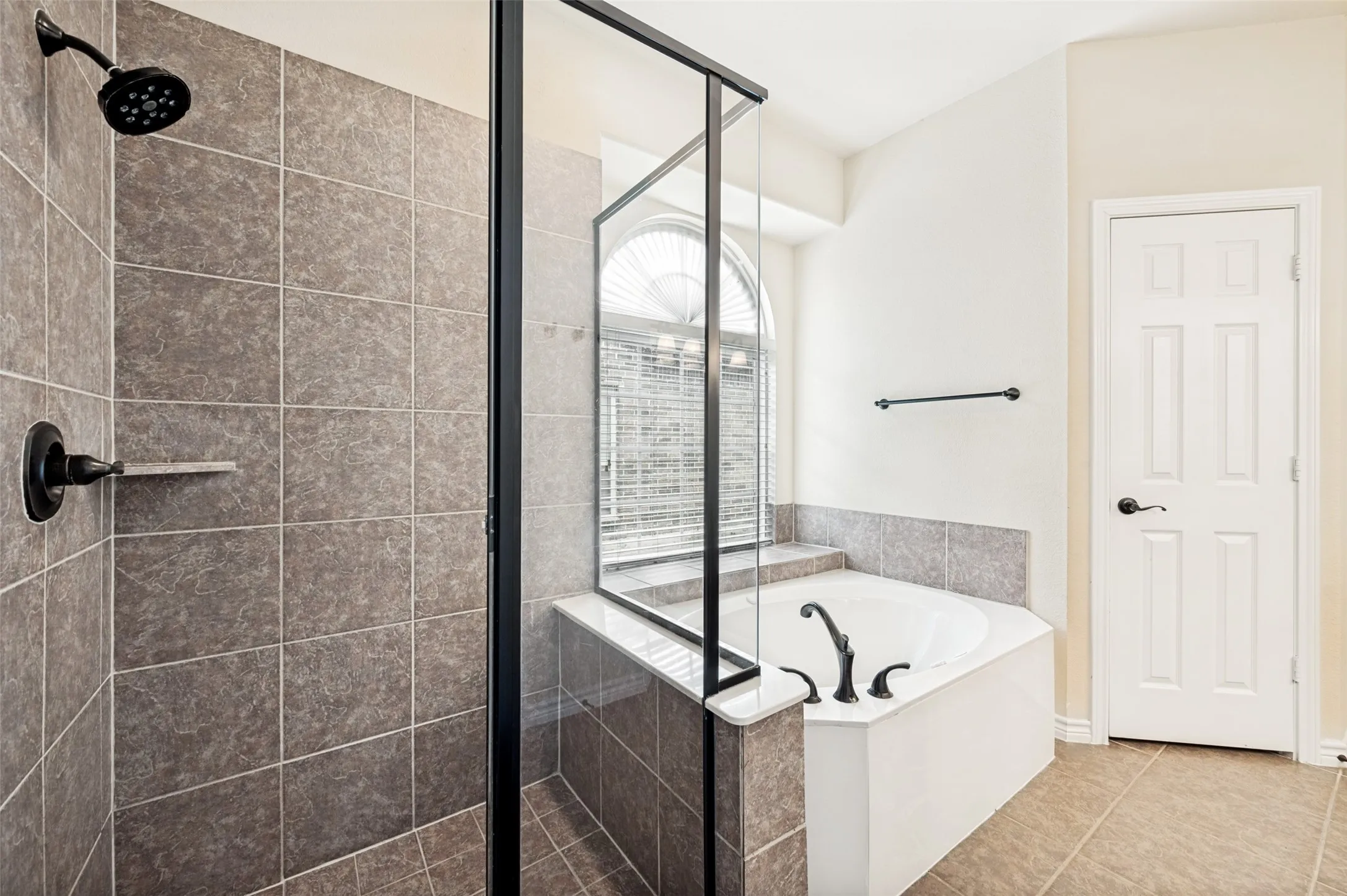 Tiled shower enclosure with dark bronze fixtures and a built-in shelf