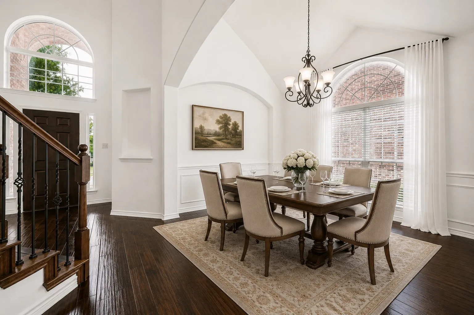 Vaulted ceiling dining area featuring wood-finish flooring, an arched window with blinds and sheer drapes, and a chandelier
Virtually staged