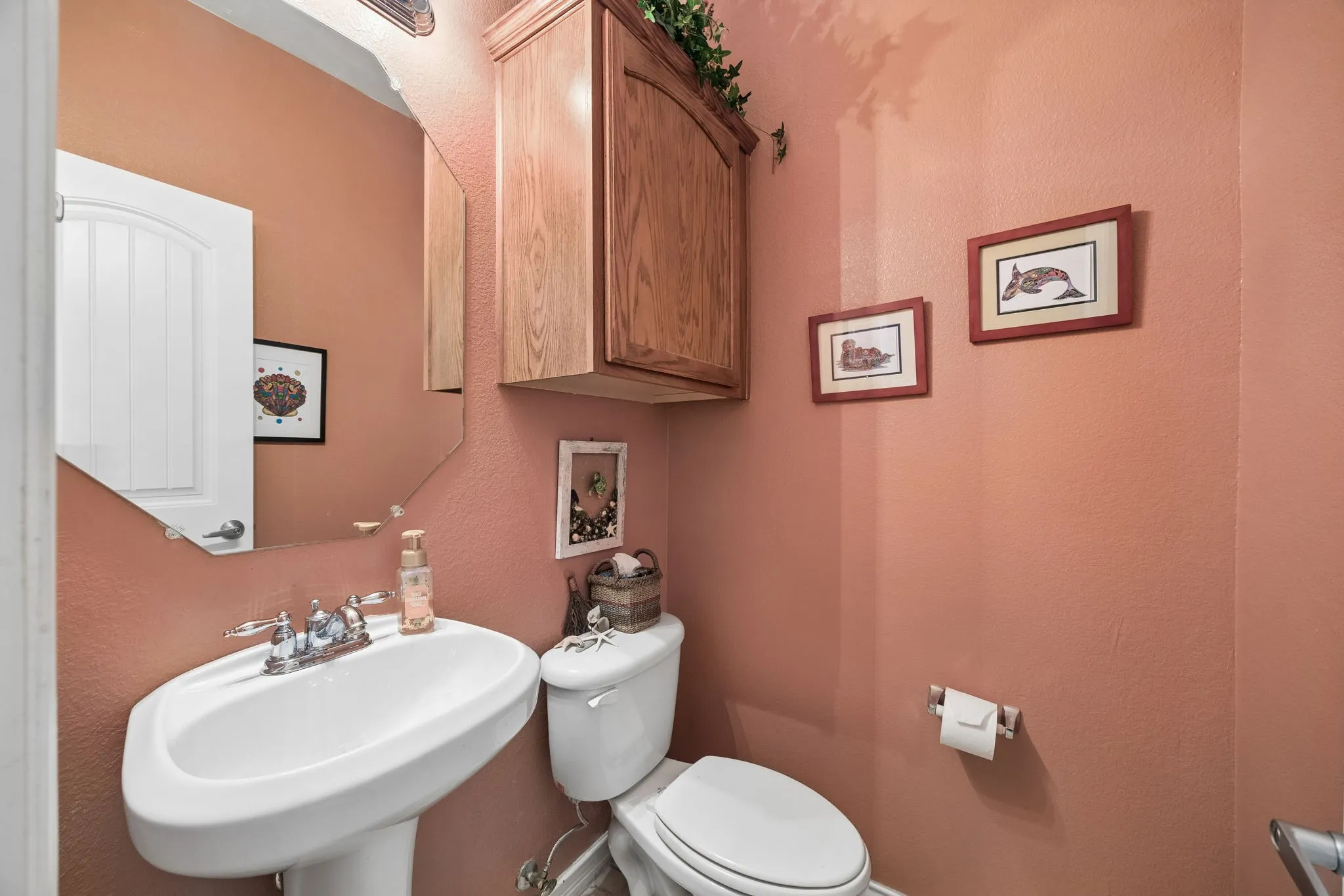 Here is the view of the first floor half bath - Charming with pedestal sink and warm designer-inspired wall color.