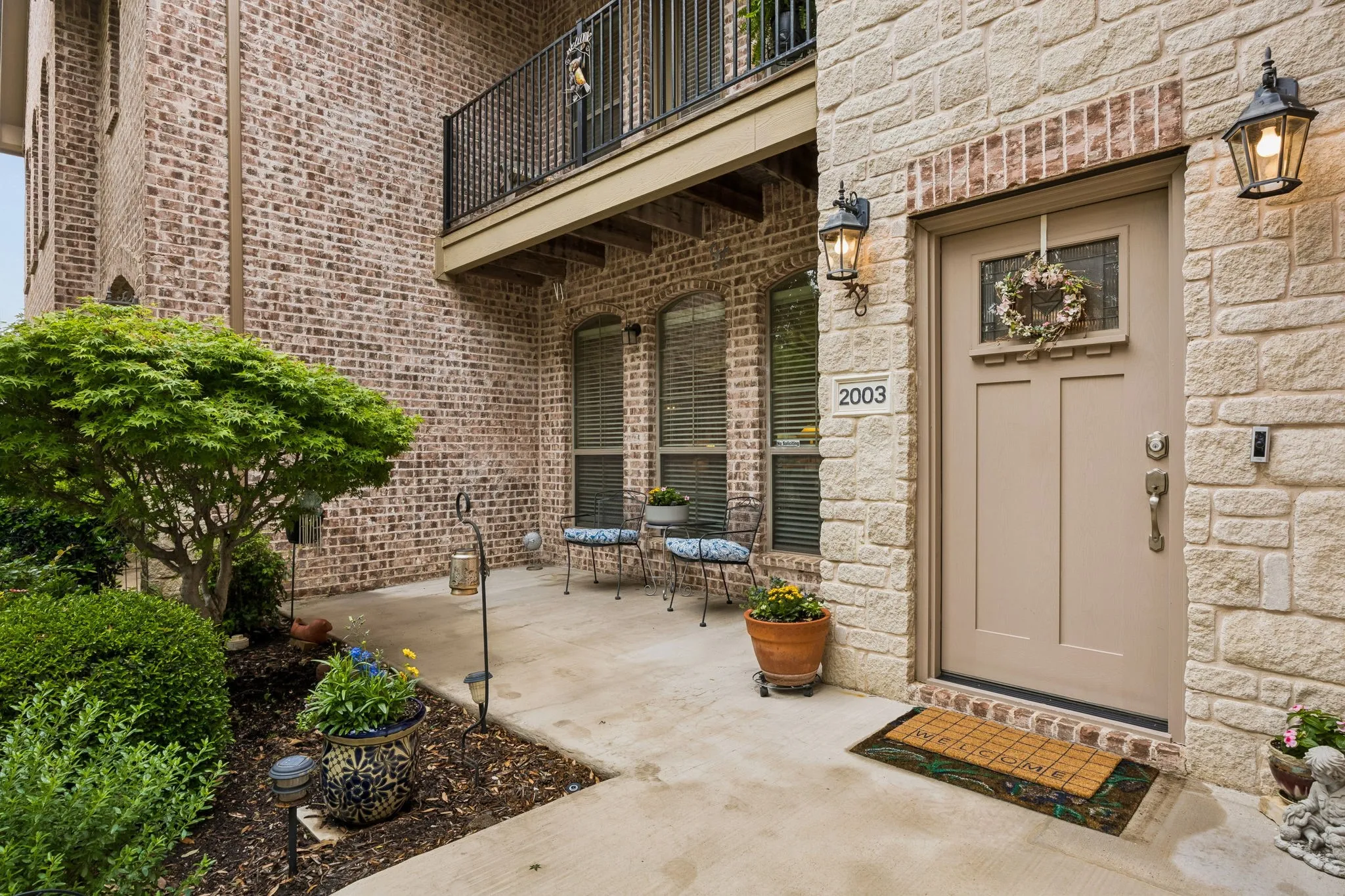 Inviting entryway enhanced by tasteful landscaping and attractive stone and brick finishes.