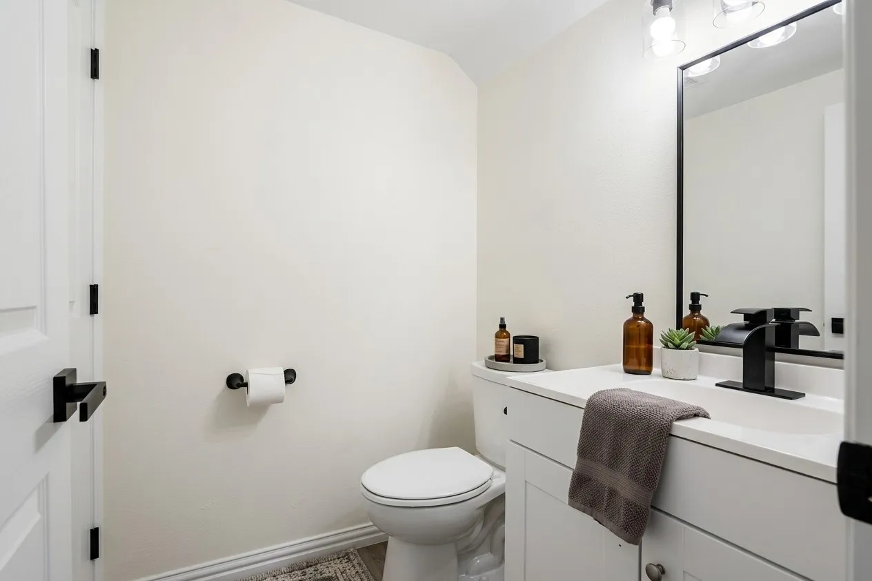 White vanity with integrated sink, black rectangular framed mirror, matte black faucet, and coordinating black hardware