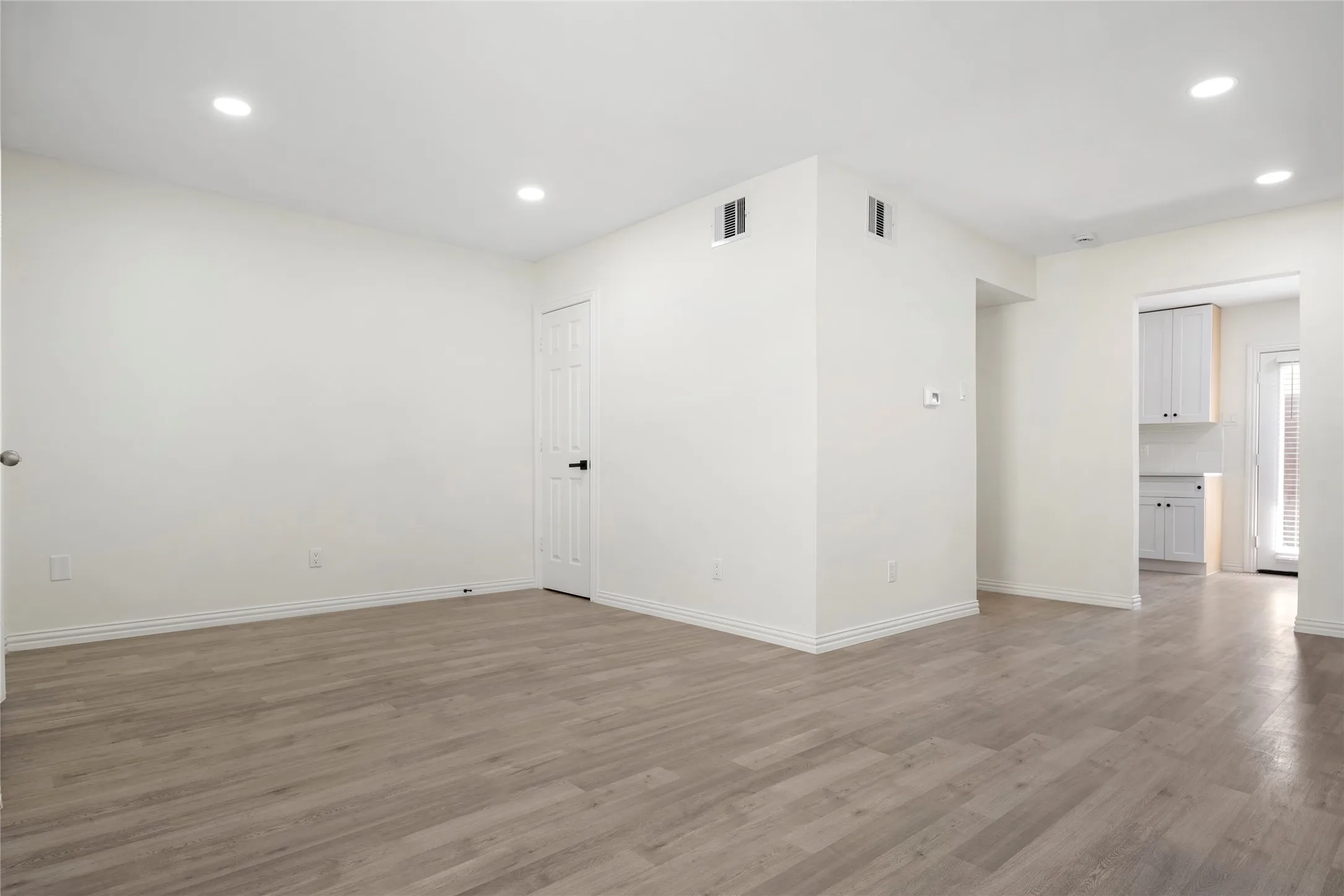 Spacious room featuring wood-finish flooring, white baseboards, and recessed lighting