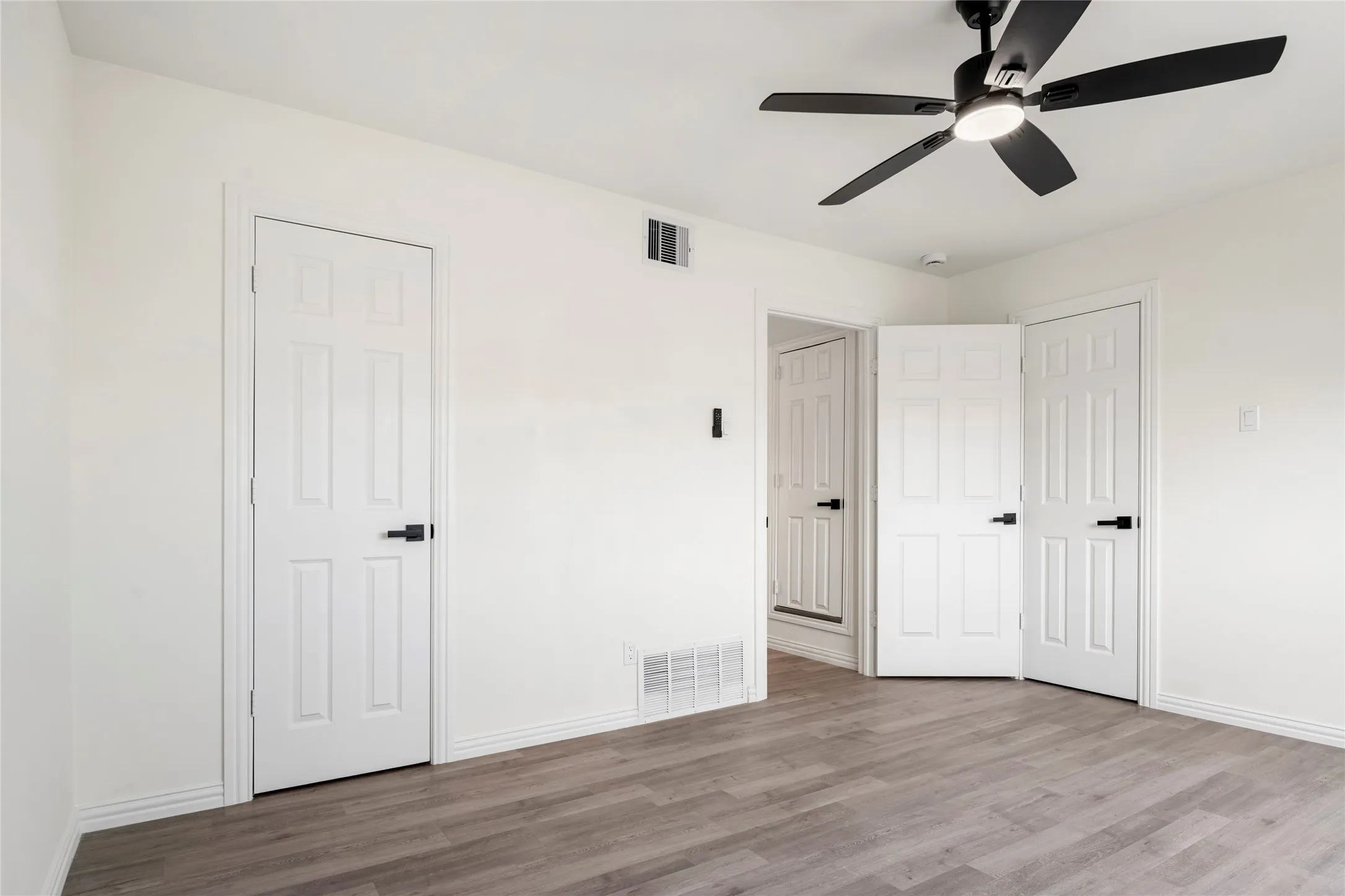 Room with wood-finish flooring, white painted walls, and white baseboards