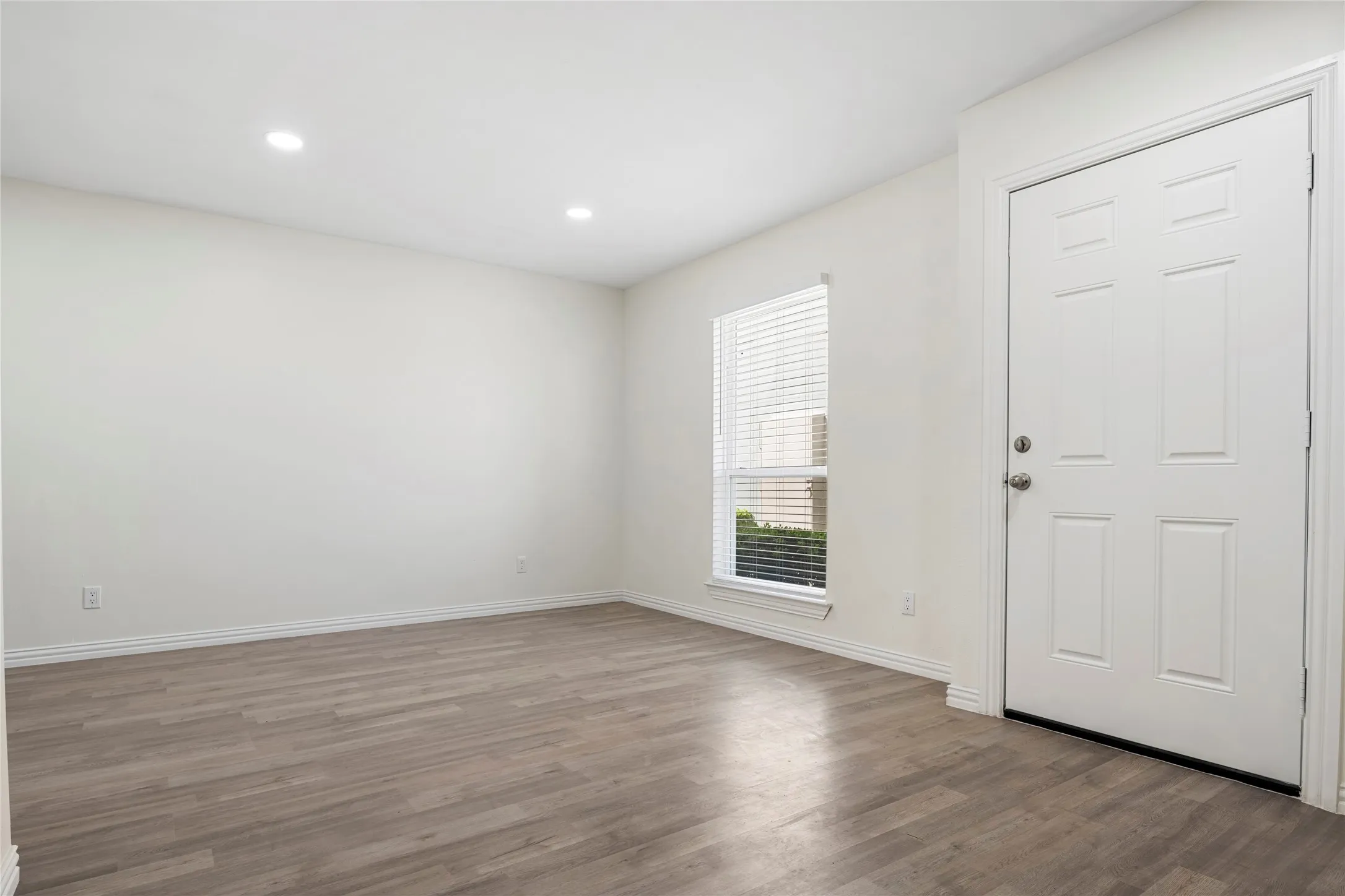 Entryway featuring a paneled door, wood-finish flooring, recessed lighting, and a window with blinds