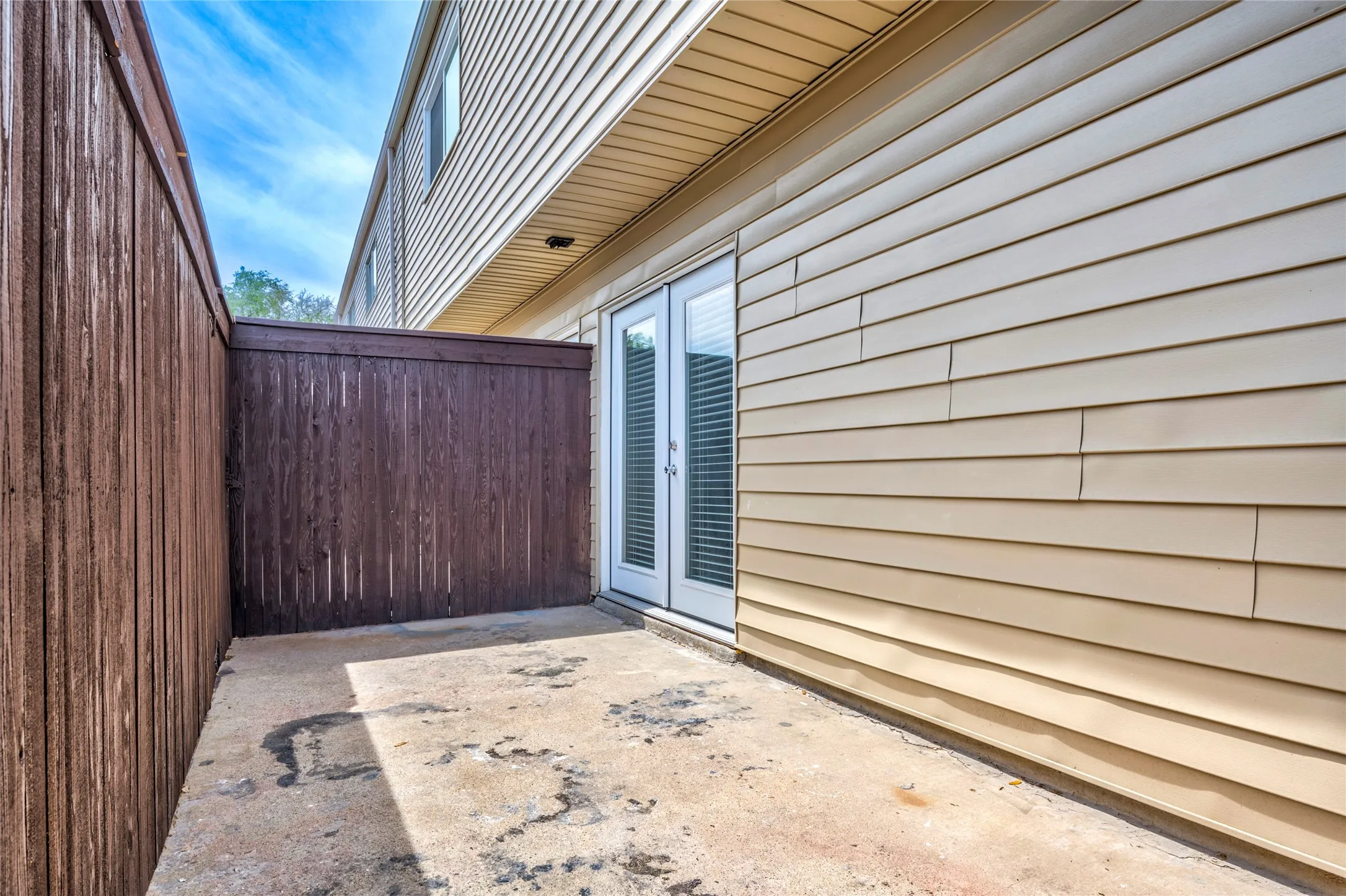 Private outdoor patio with privacy fencing and direct access via double glass doors