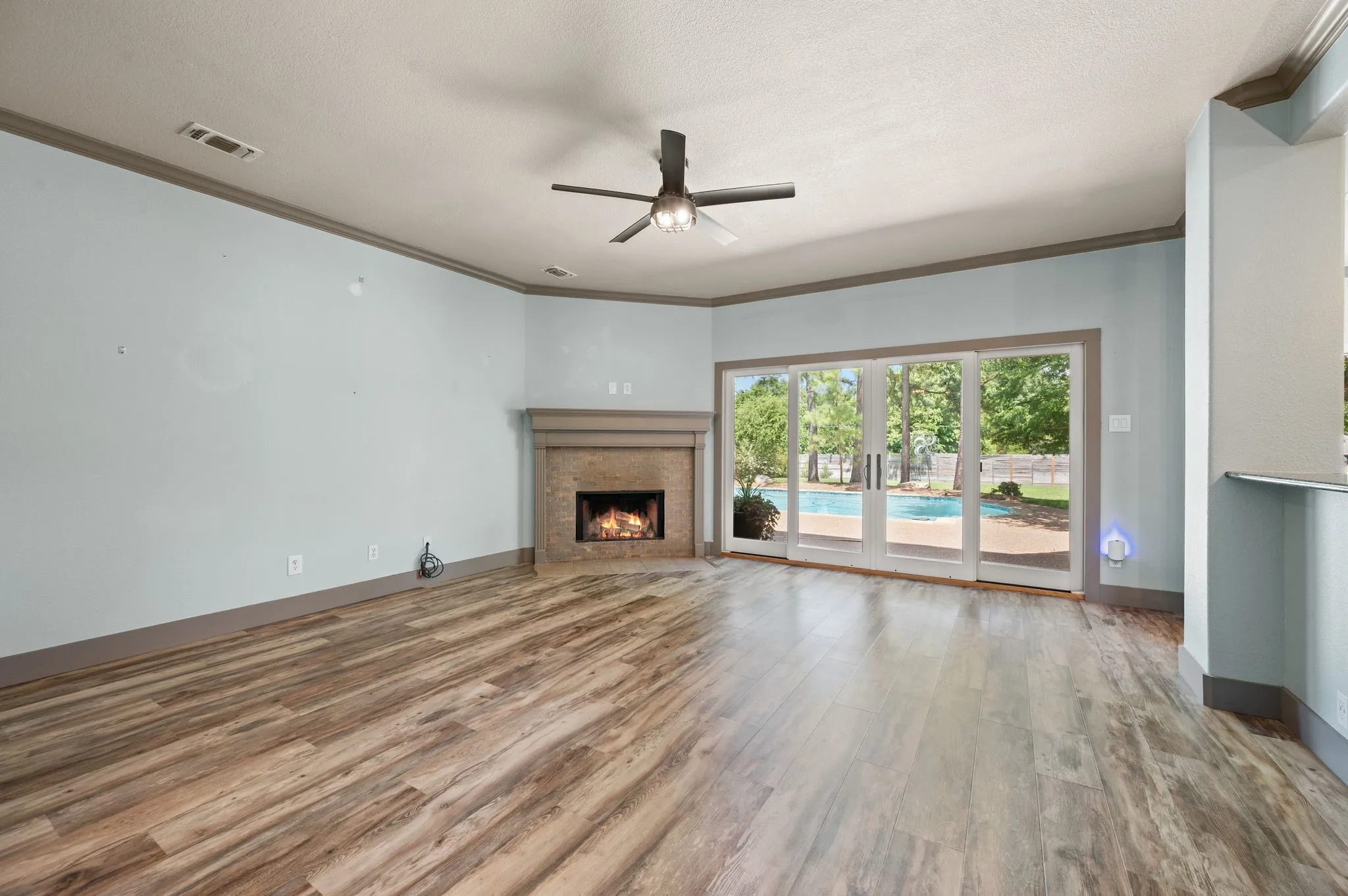 The oversized living room has a corner wood burning fireplace and stackable sliding glass doors for an unobstructed view of the gorgeous backyard. Flooring is LVT.