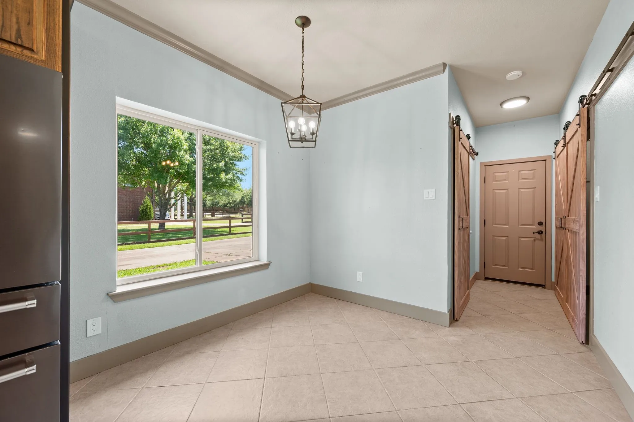 Additional dining space with beautiful windows and farmhouse lighting. Barn doors open to laundry room and pantry. Exit door leads to garage.