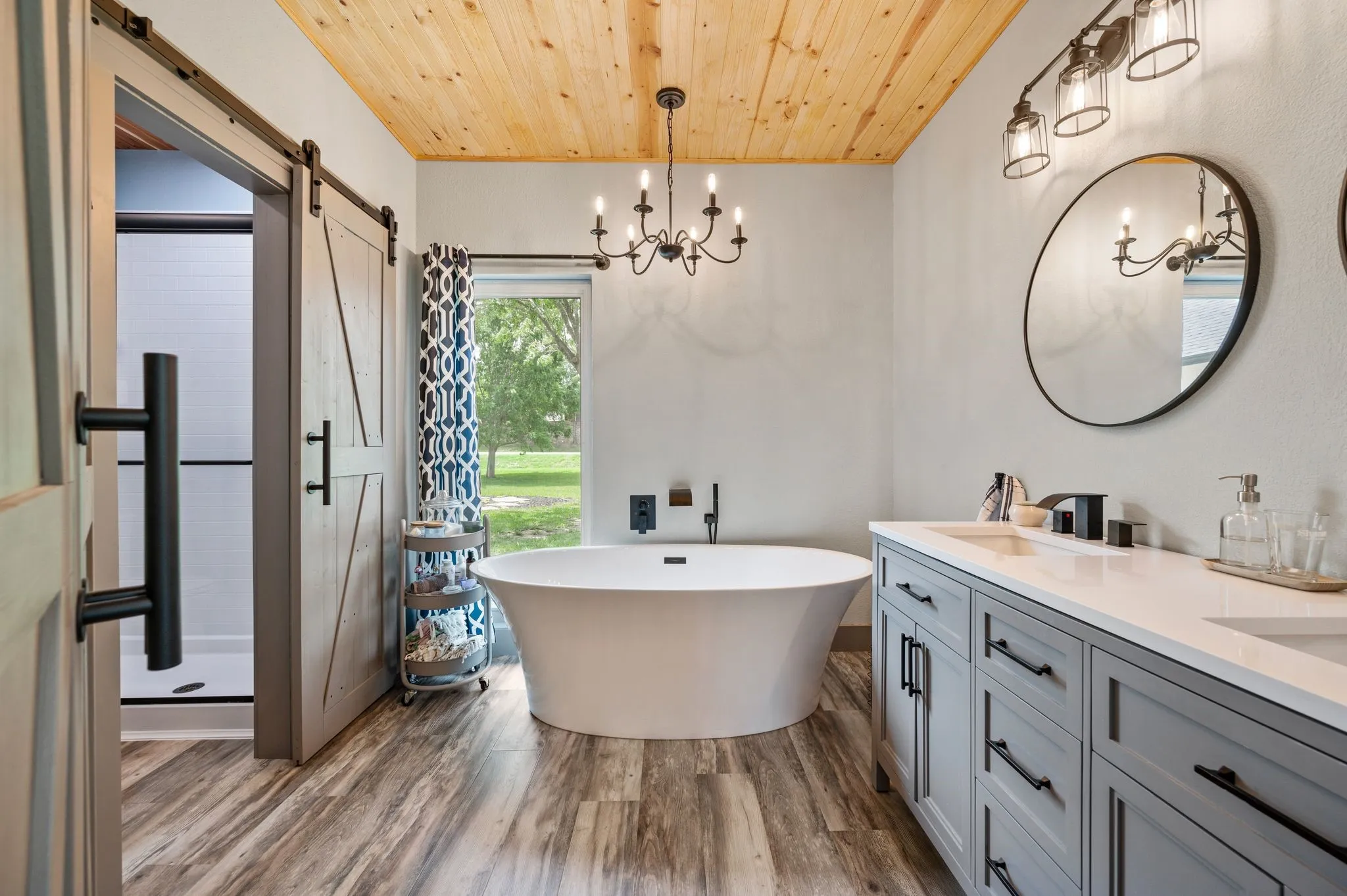 This fully updated Primary bath, completed in 2025, is well appointed and includes a deep soaking tub, a quartz topped dual sink vanity, LVT flooring, barn doors and farmhouse fixtures and hardware.