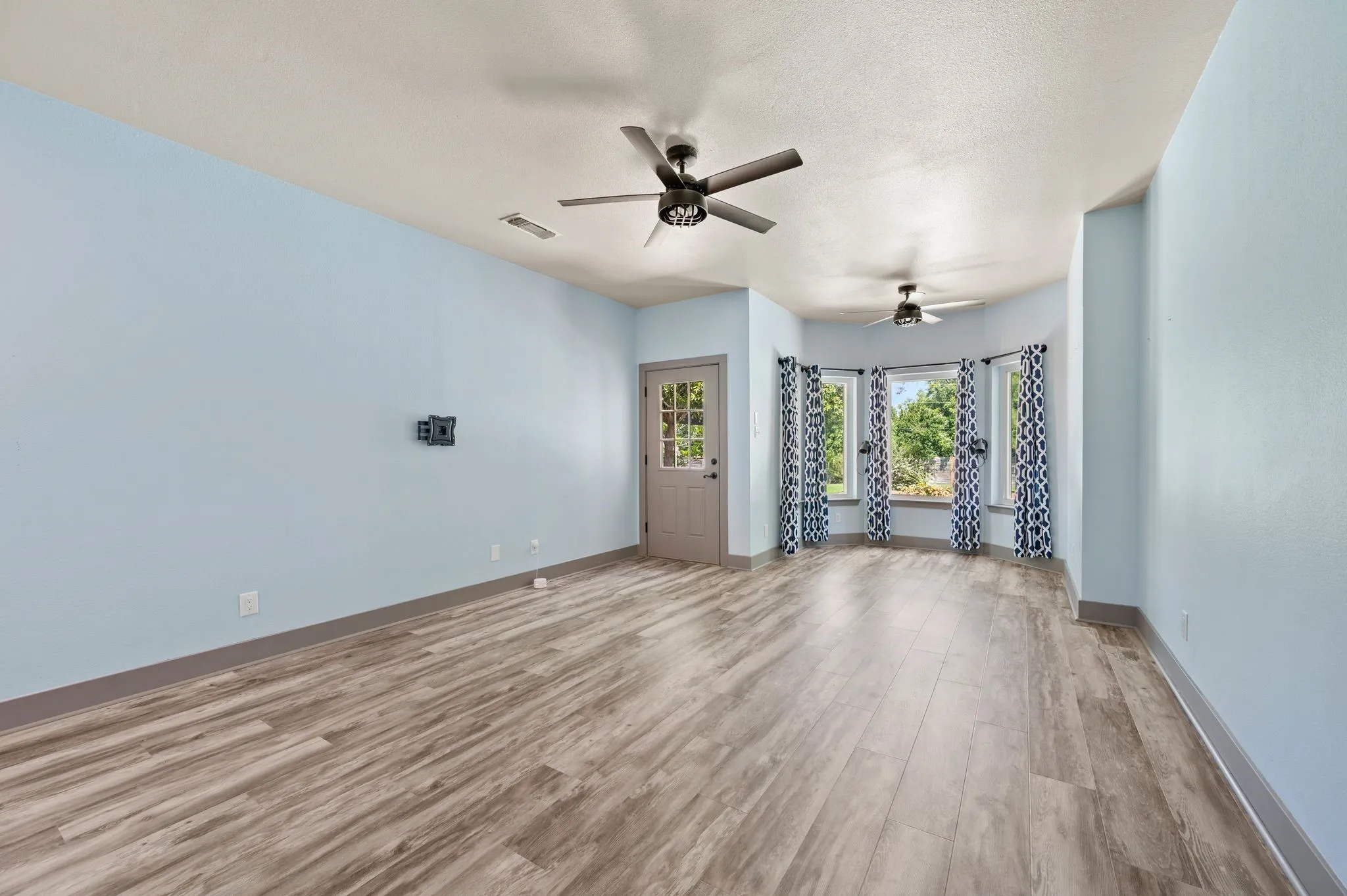 The spacious Primary Bedroom with ensuite bath is located downstairs has a large bay window for additional sitting space and an exit door to the pool and backyard. It includes Luxury Vinyl Tile (LTV) flooring and two ceiling fans.