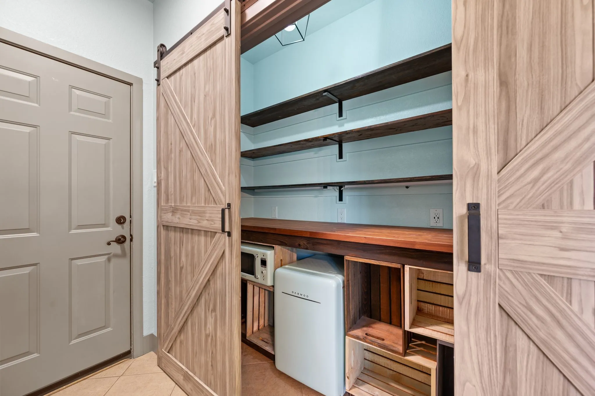 Fantastic pantry with barn door access comes with a beverage refrigerator and a microwave. The space includes under-counter lighting and multiple electrical outlets.