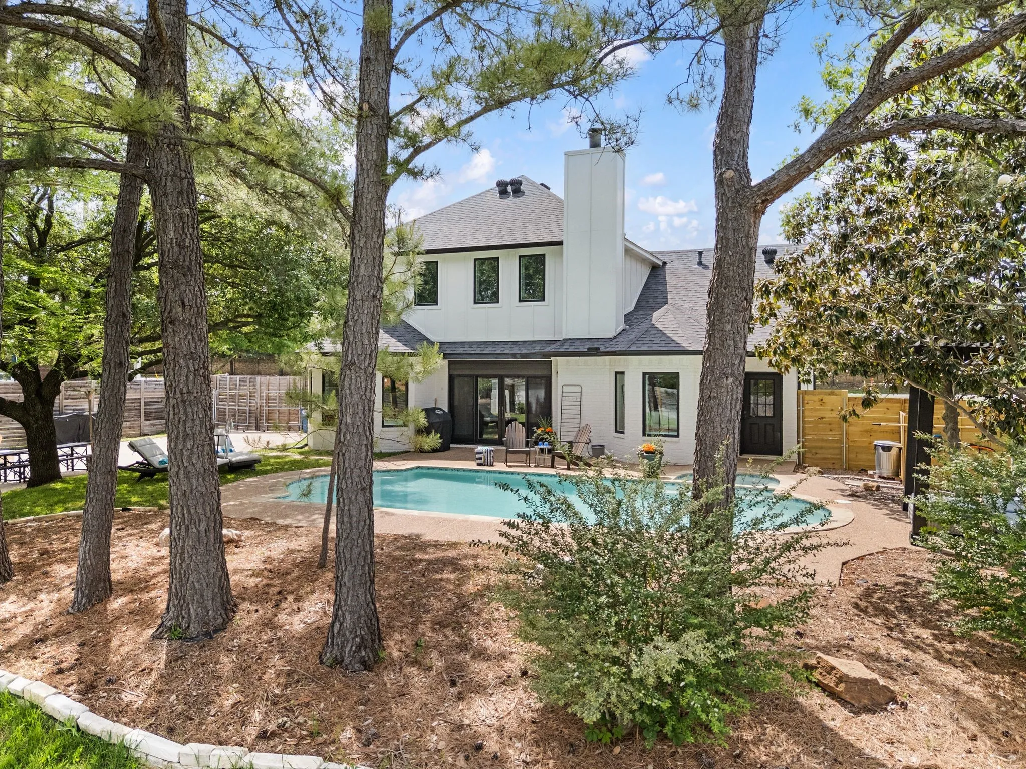 Beautiful trees and landscaping surround the pool and patio.