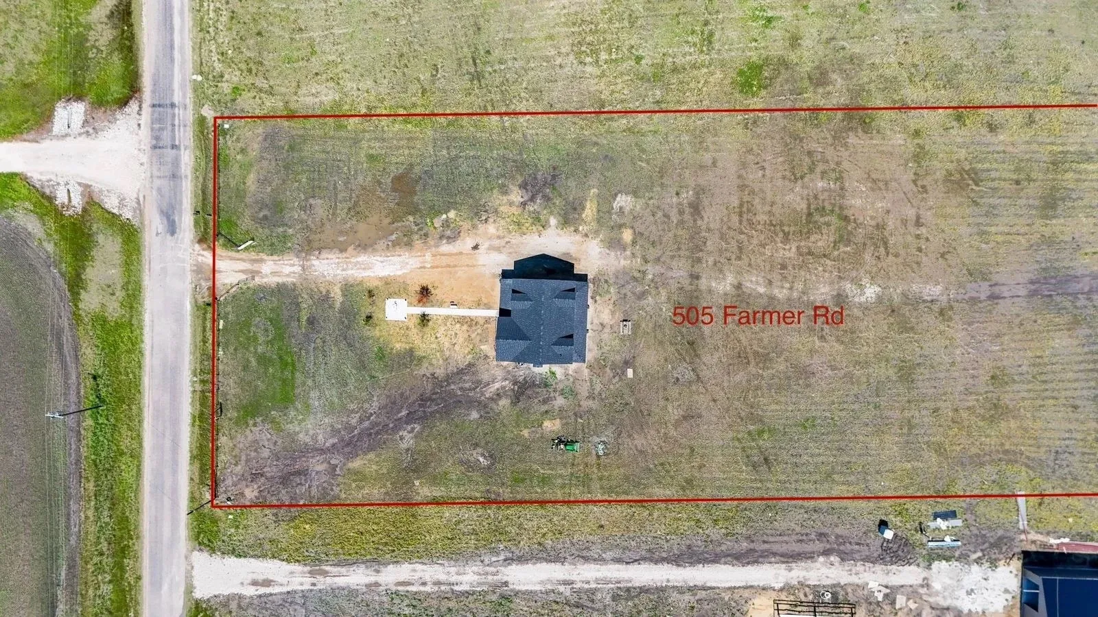 Aerial property overview showcasing a single-story residence with a dark shingled roof, set on an expansive parcel of land