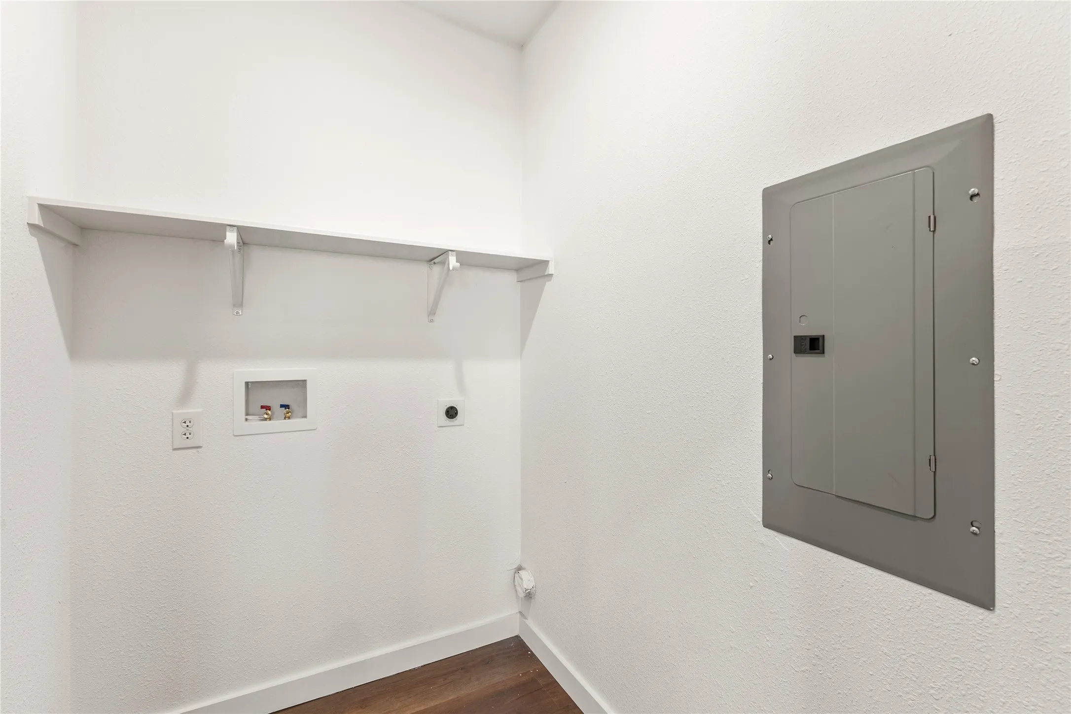 Utility area with wood-finish flooring, white walls, and built-in shelving