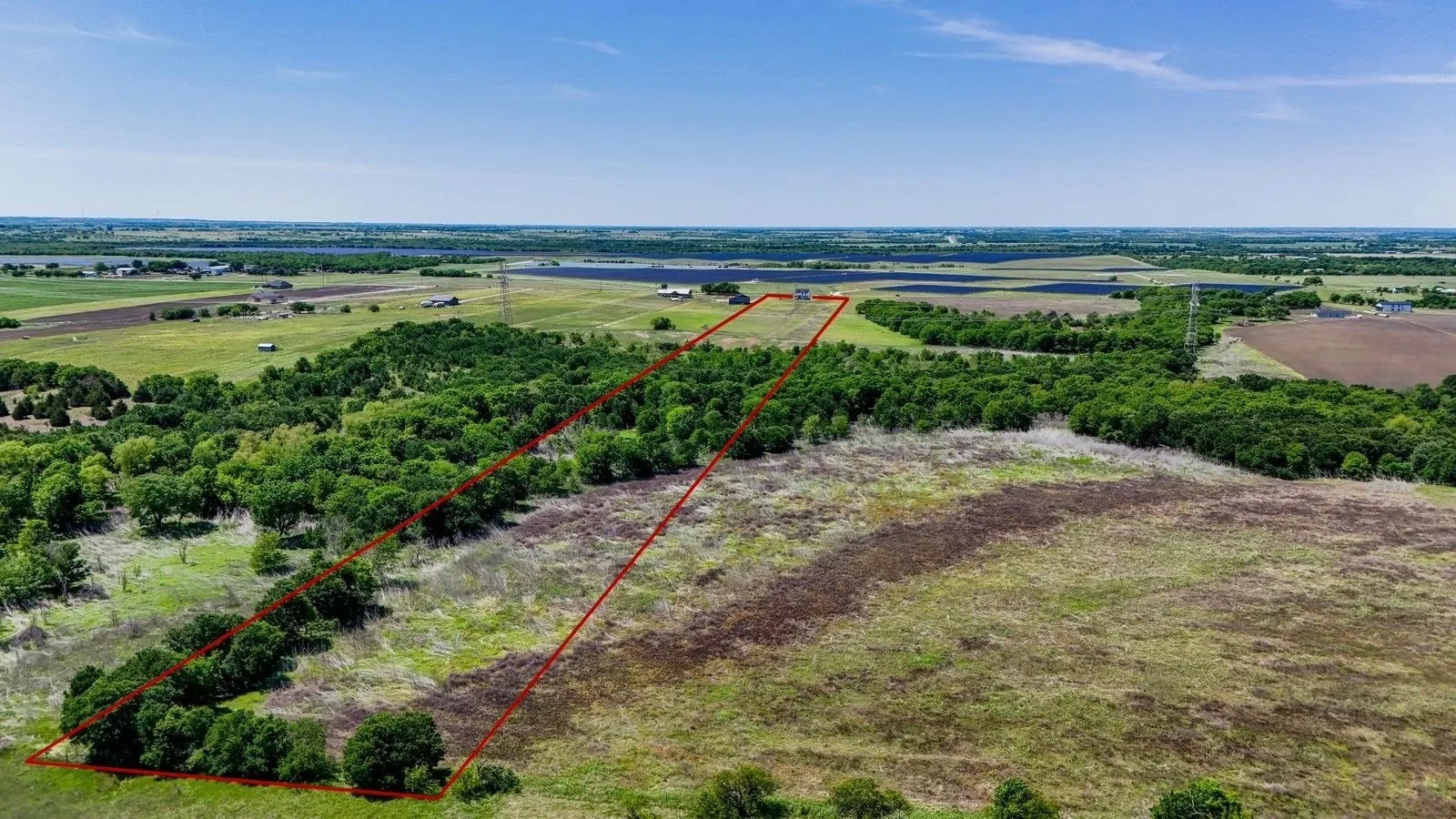 Expansive land parcel featuring a mix of open fields and mature tree lines