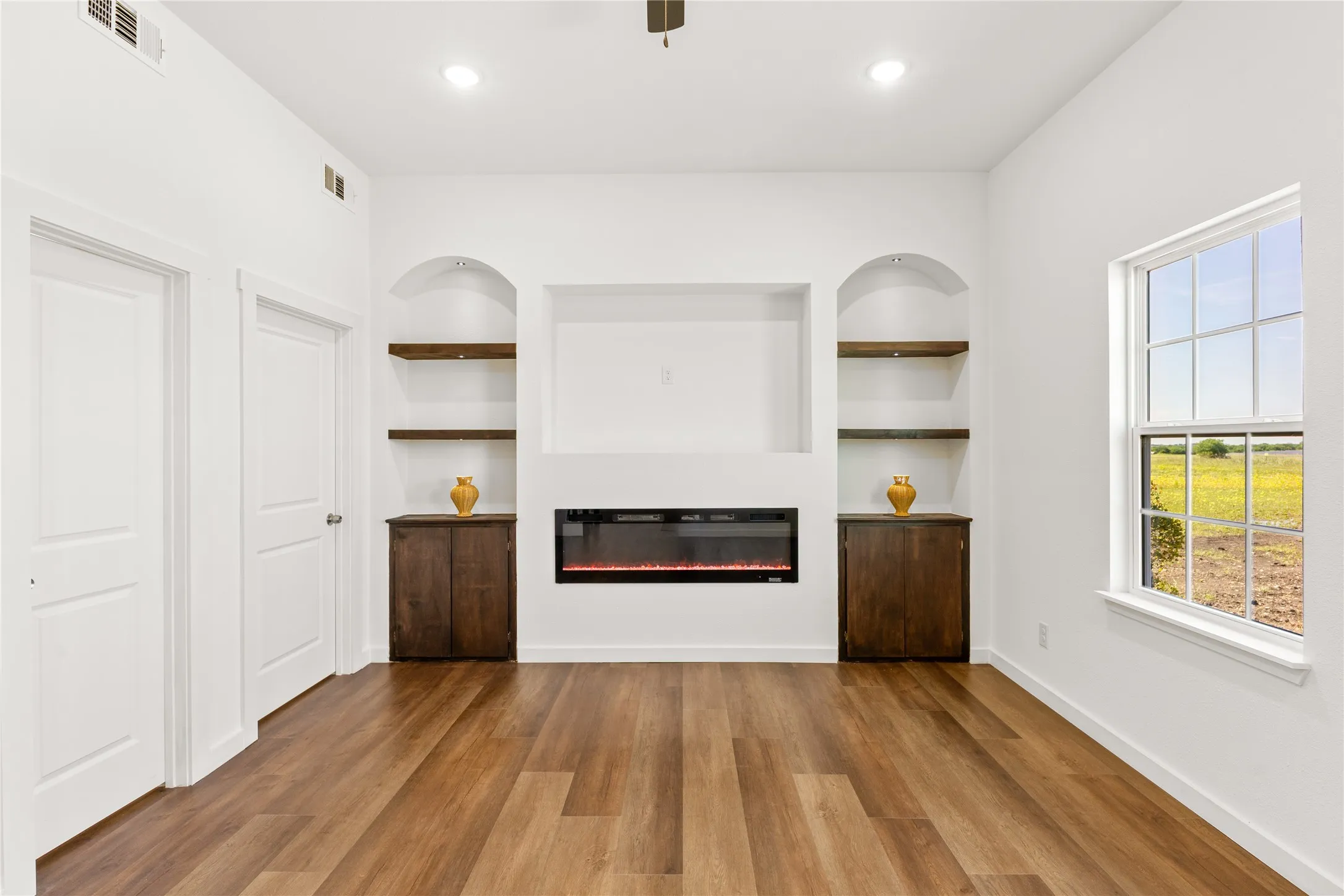 Integrated media center featuring an electric fireplace, built-in shelving, and dark wood-finish cabinetry