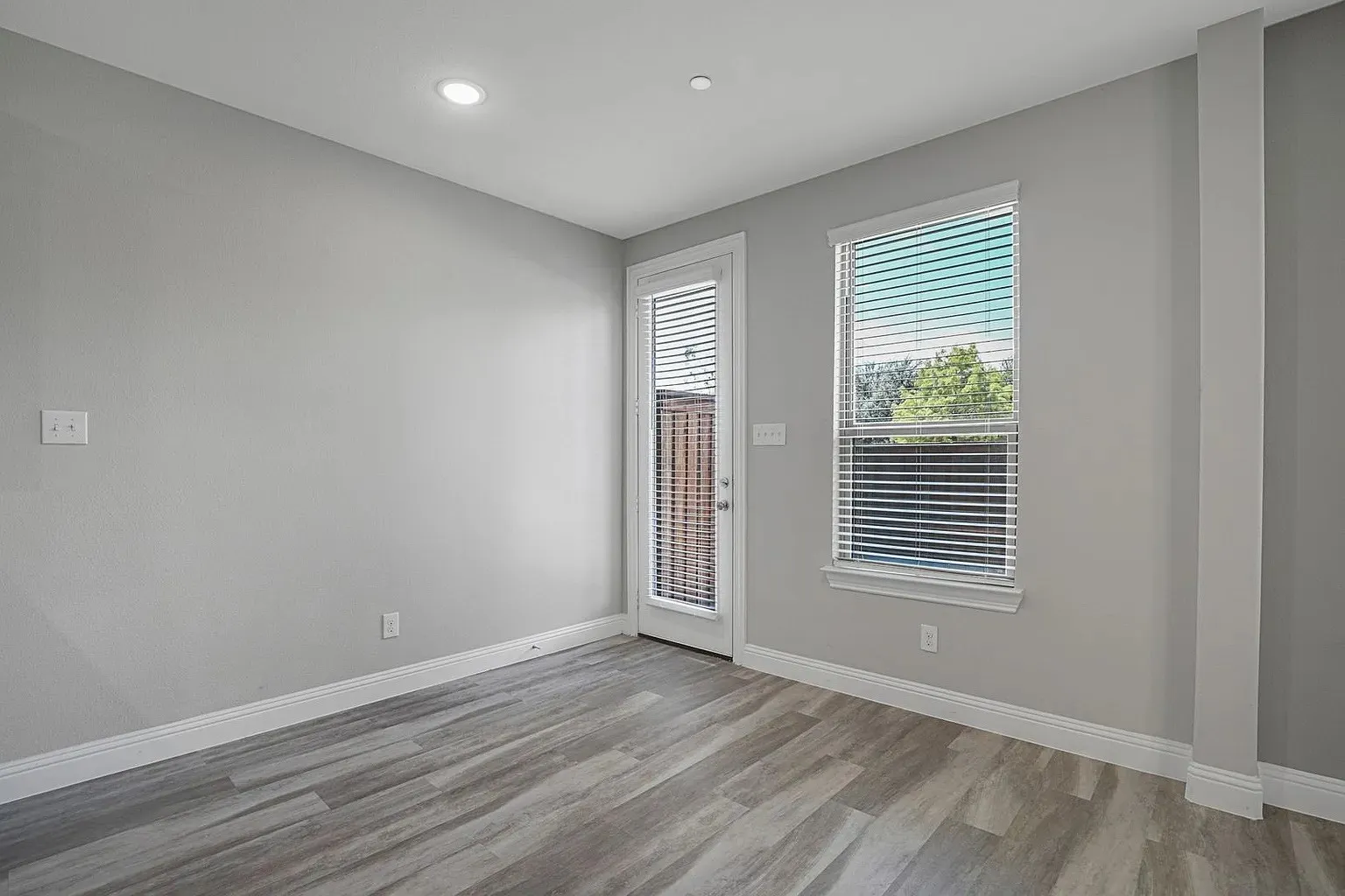 Light gray walls complement the wood-finish flooring in this room featuring a white trim package