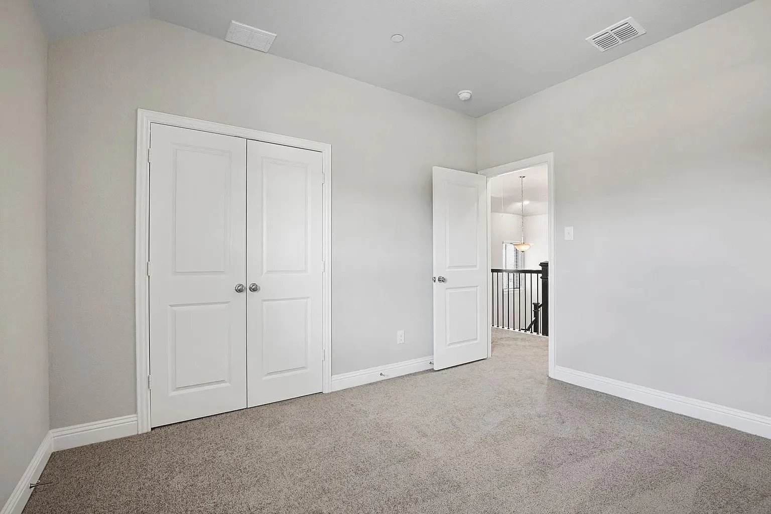 Carpeted room featuring light gray walls, white trim, and a white bi-fold closet door