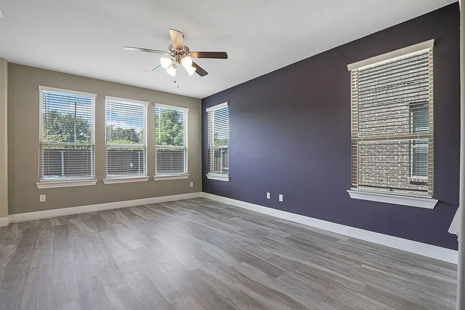 Spacious room featuring light wood-finish flooring and a multi-speed ceiling fan with integrated lighting