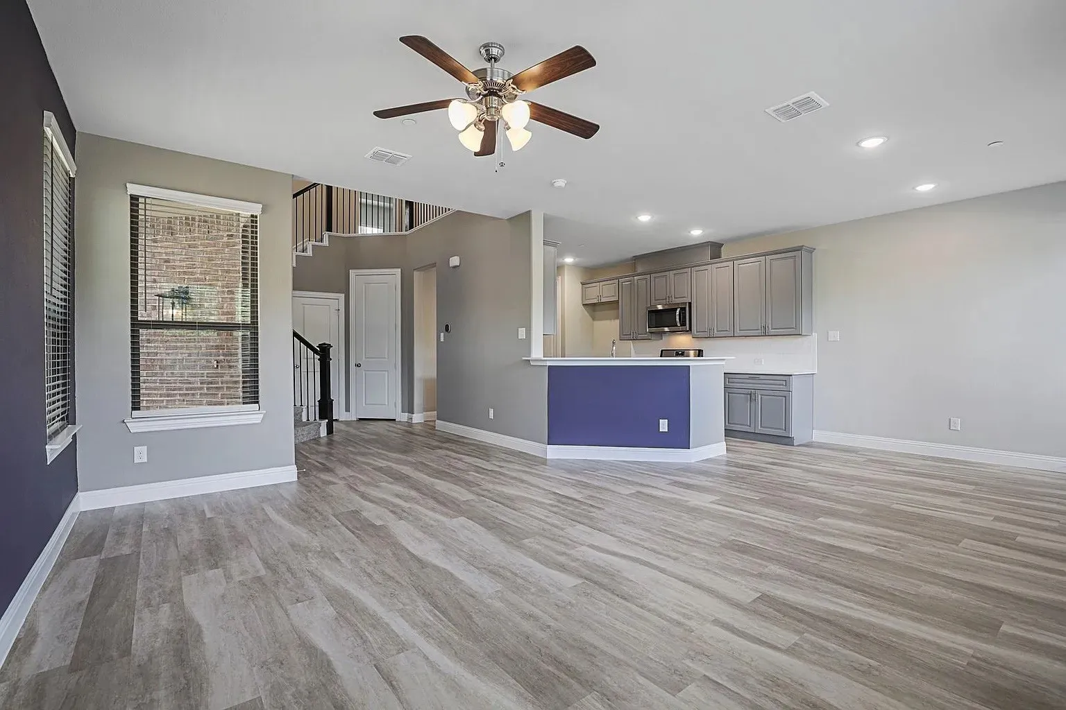 Spacious open-concept living area featuring wood-finish flooring, a ceiling fan, and recessed lighting