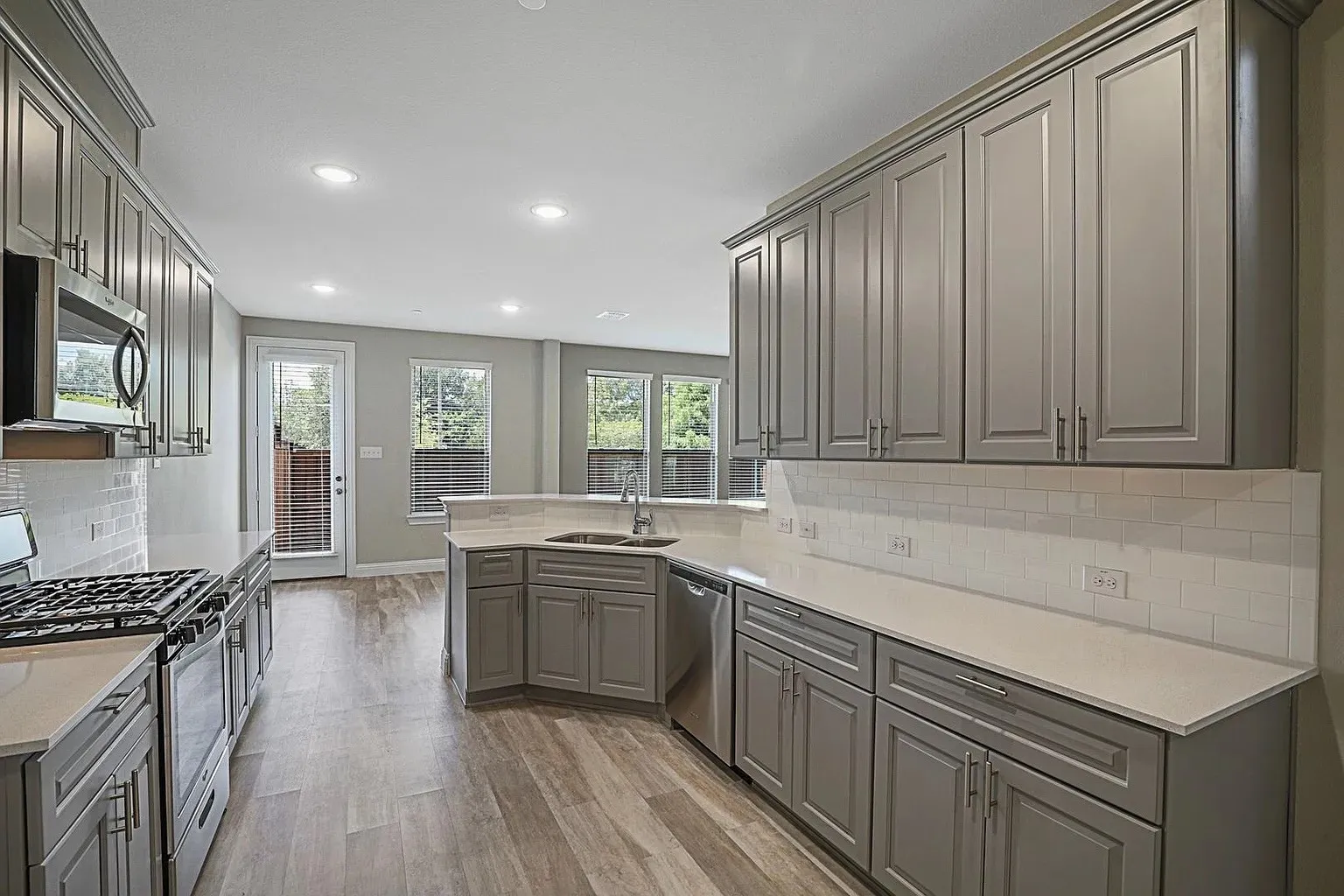 Modern kitchen featuring wood-finish flooring and grey shaker-style cabinetry