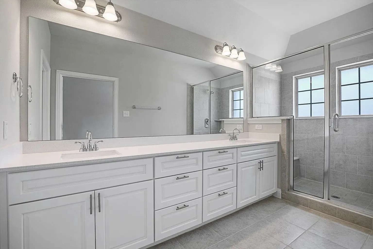 Spacious bathroom featuring an extended double vanity with quartz countertops, undermount sinks, and ample white cabinetry