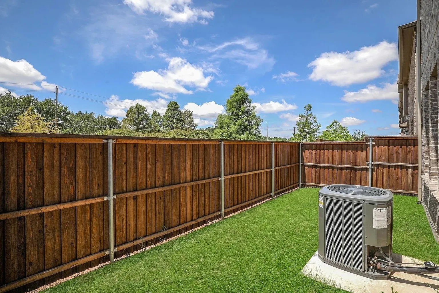 Private outdoor space featuring a wood fence, green lawn, and brick exterior
