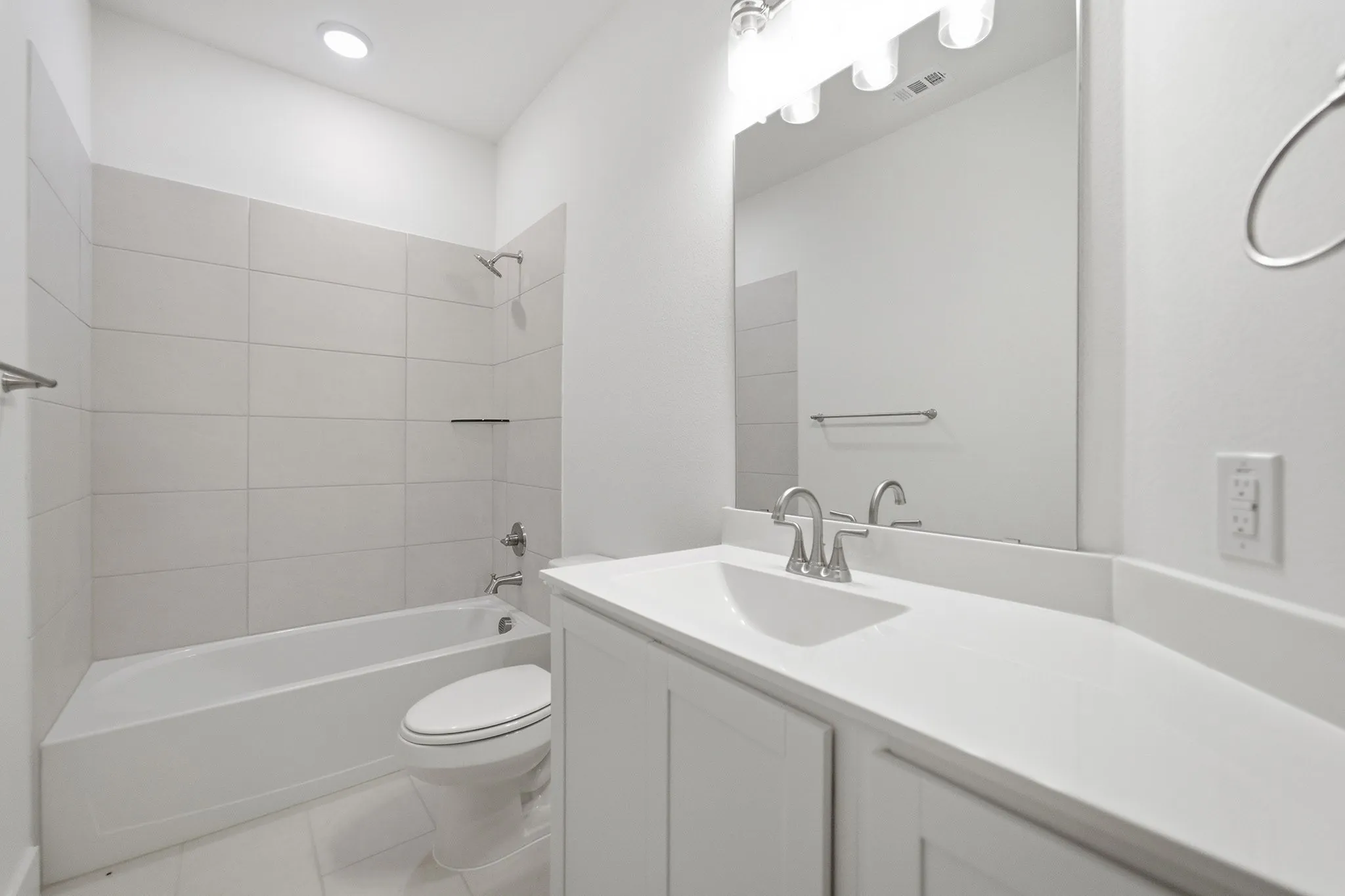 Bright bathroom featuring a single vanity with a white countertop, undermount sink, and a large mirror