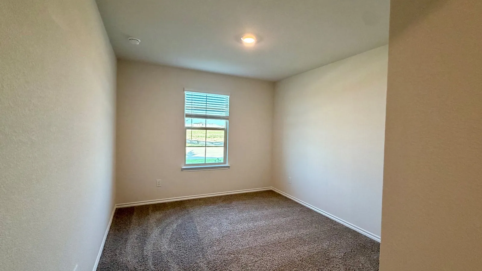 Carpeted room with a single window featuring horizontal blinds, recessed lighting, and neutral wall paint